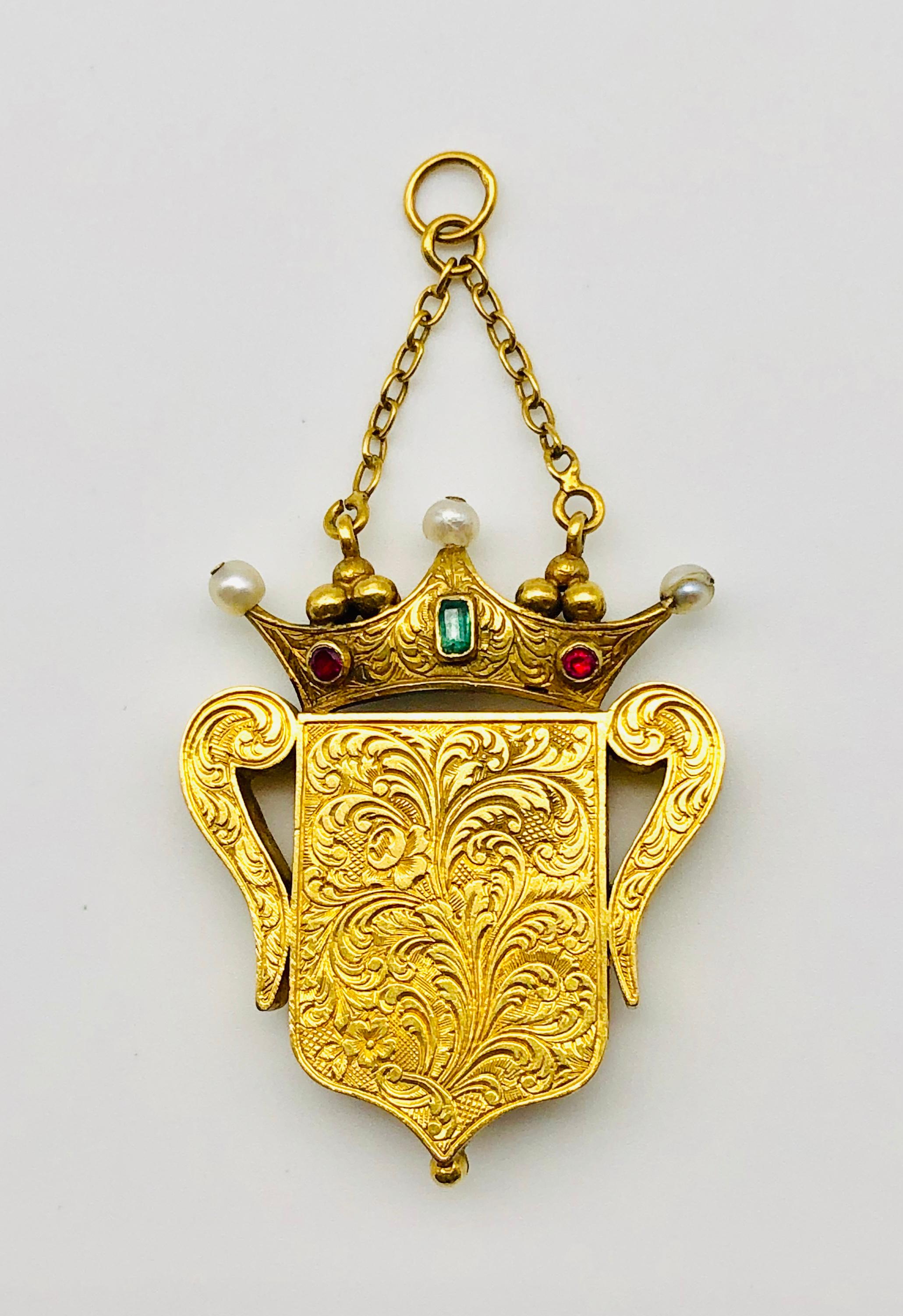 Very exquisite vinaigrette in the shape of a shield decorated with a forget-me-not set with turquoises. From two chains a crown is suspended that holds the vinaigrette. The three jagged crown is decorated with orient pearls, four rubies and two