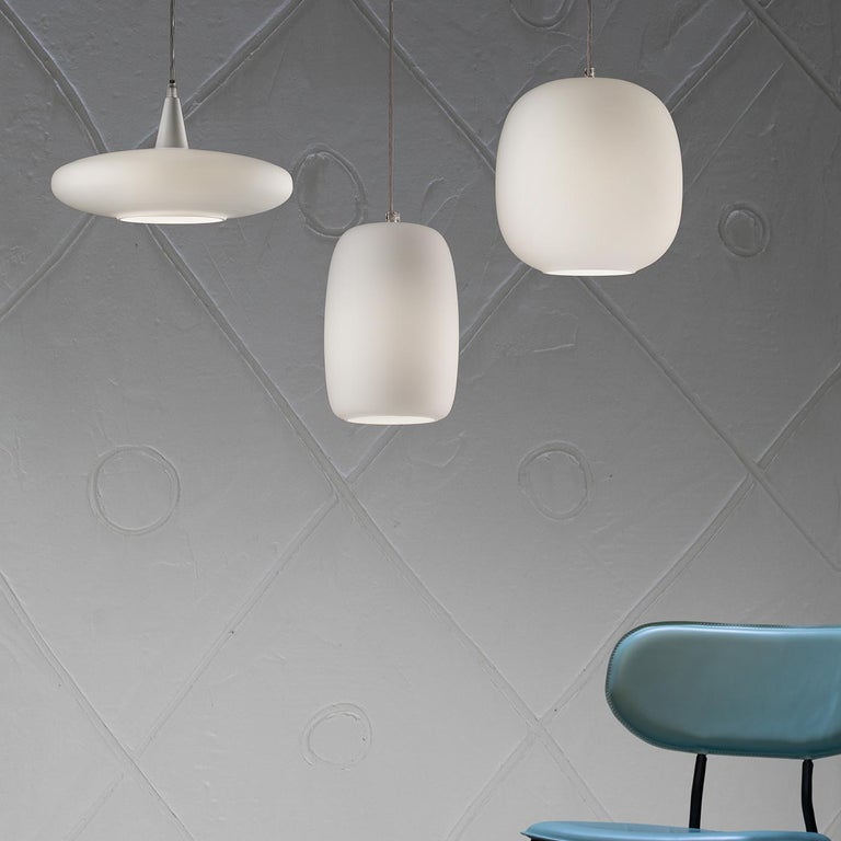 Modern and minimalist, this pendant lamp will find its home suspended over a dining table in a contemporary interior. The fluid shape of the diffuser in white glass is obtained by blowing the glass inside a mold for an impeccable result telling the