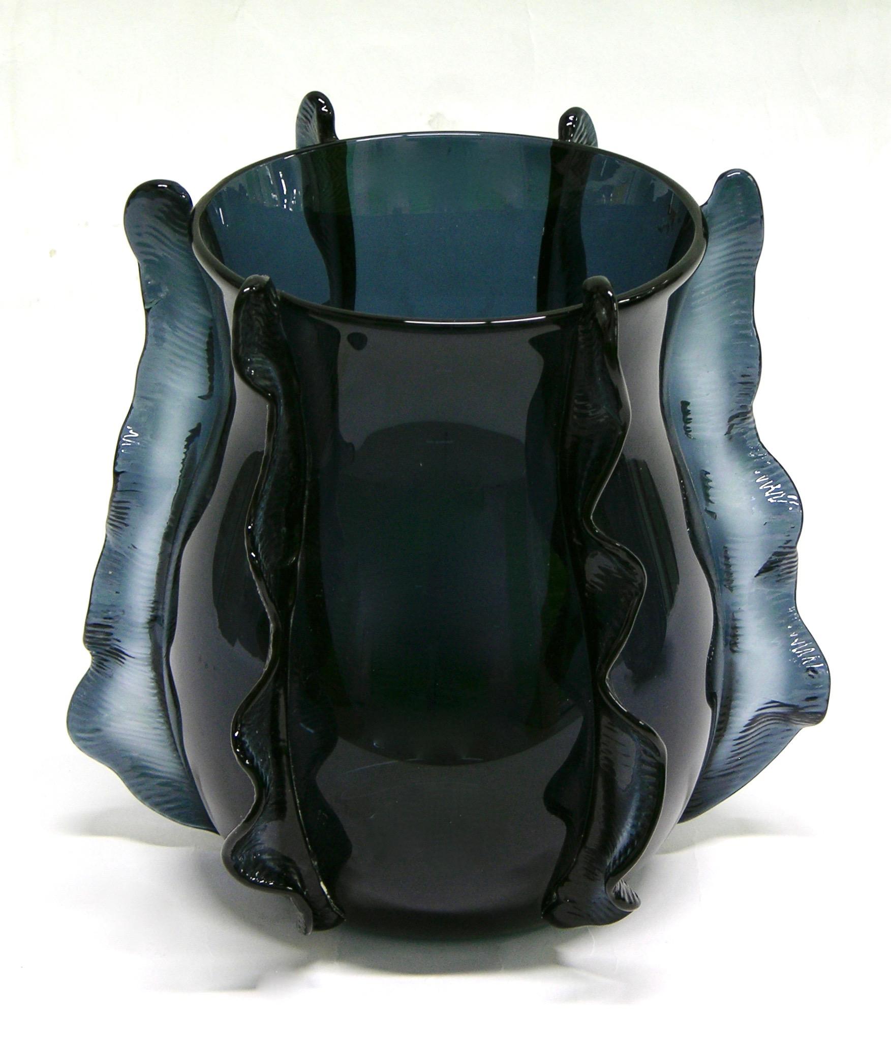 A Venetian organic vase in blown Murano glass, created in a very rare avio navy blue color, the curved shape sensually enhanced with waved handcrafted incised decorations in relief, like frills in motion that embrace and lift the design. Signed