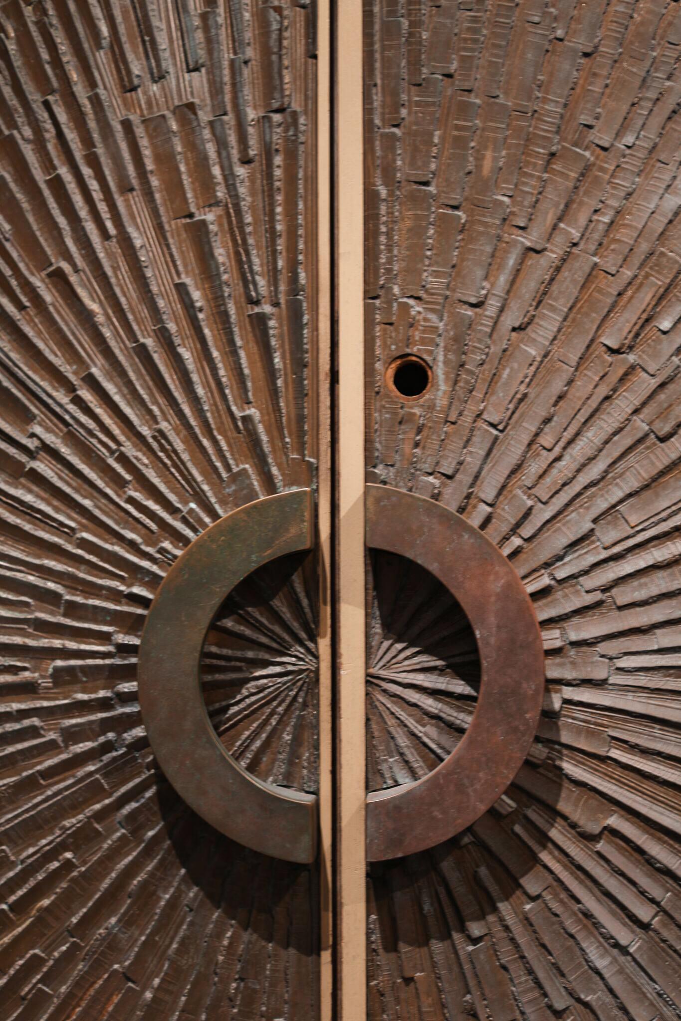 Pair of Heroic sunburst double sided bronze door designed by Billy Joe Mc Carrol and David Gillespie for Forms and Surfaces. Patinated bronze pattern on interior and exterior. Both sides feature original semicircular solid bronze handles. Finish on