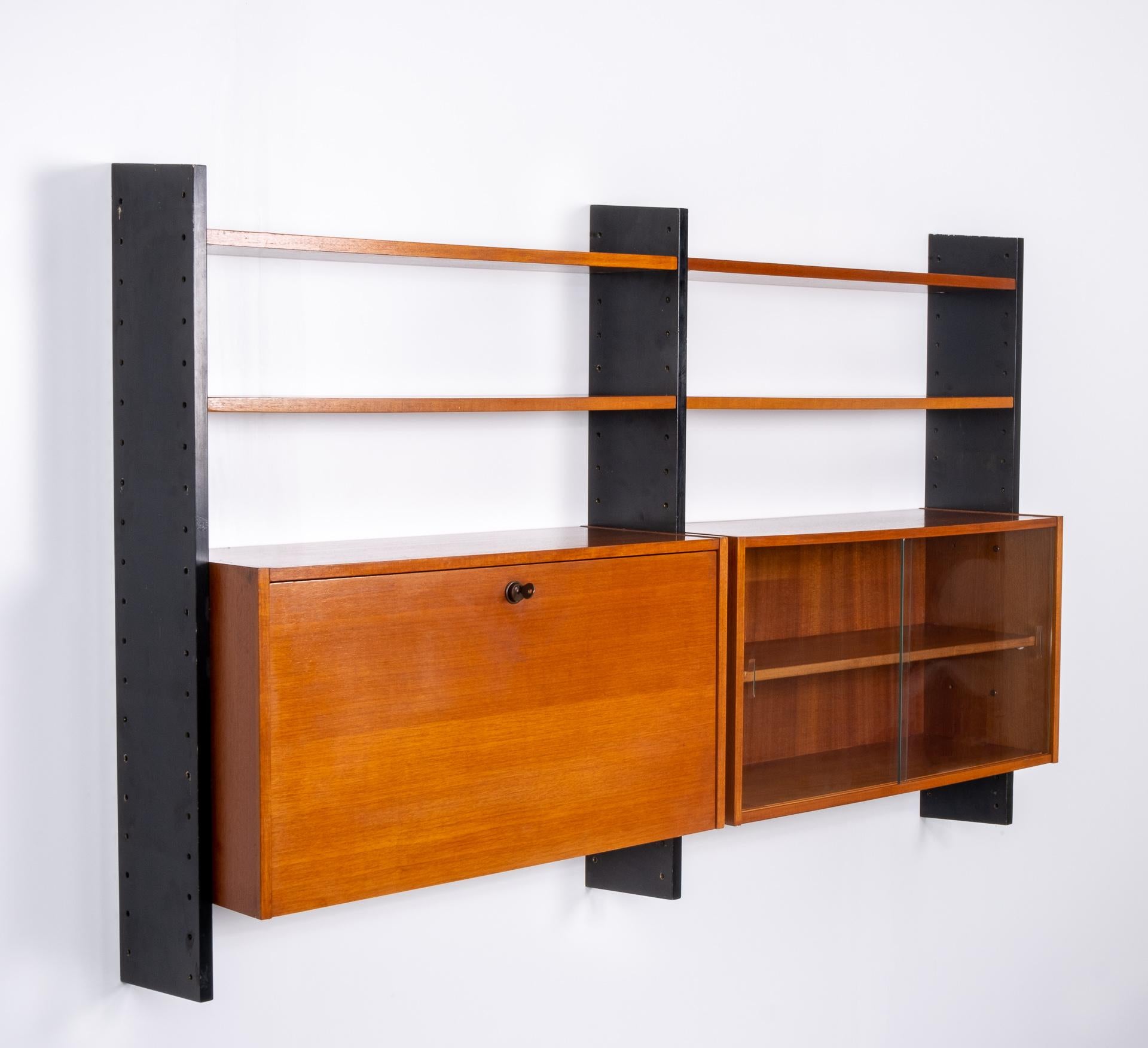 Very nice wall system. Produced by Formule Kempes meubelen Waddinxveen Holland, 1960s.
Three black uprights. With 4 teak wood shelves. And two cabinets, one with glass sliding doors and one with a valve secretary comes with 3 little drawers and a