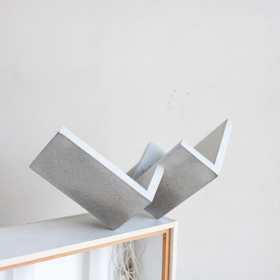 Handcrafted geometrical concrete sculpture Formworks #1 by Spanish designer Manolo Menéndez. It can be used as a centerpiece and book and magazine holder. 
A collection of 10 sculptural pieces designed in a minimalist architectural language that
