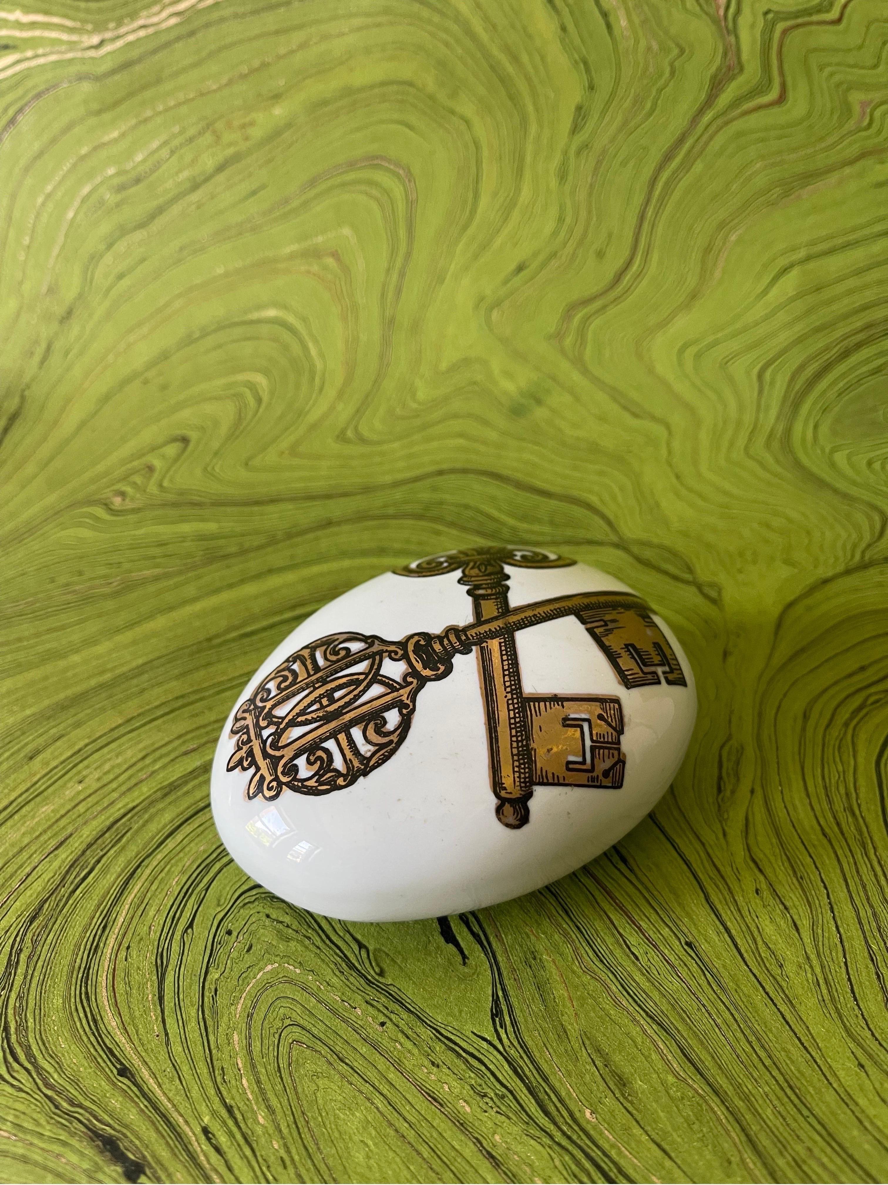 Is there anything that feels better in the hand than a Fornasetti stone? This hollow white glazed ceramic transferware paperweight with hand applied gold detail is in excellent vintage condition with one glaze fleck under the key on the right side
