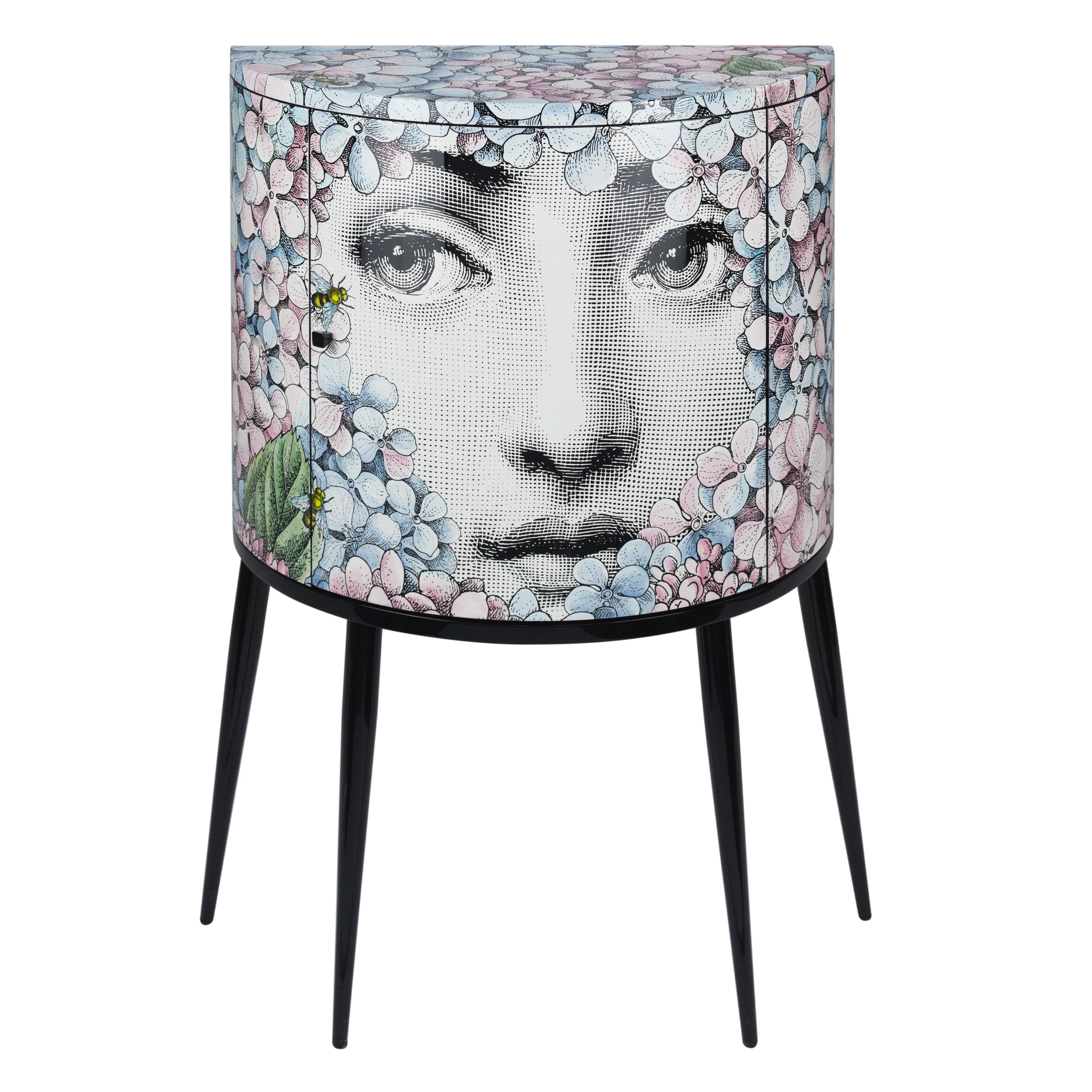 The consolle is handcrafted using original artisan techniques, like all Fornasetti pieces of furniture.
This consolle is silk-screened by hand, hand painted and covered with a smooth lacquer.

The decoration depicts a variation on the iconic face