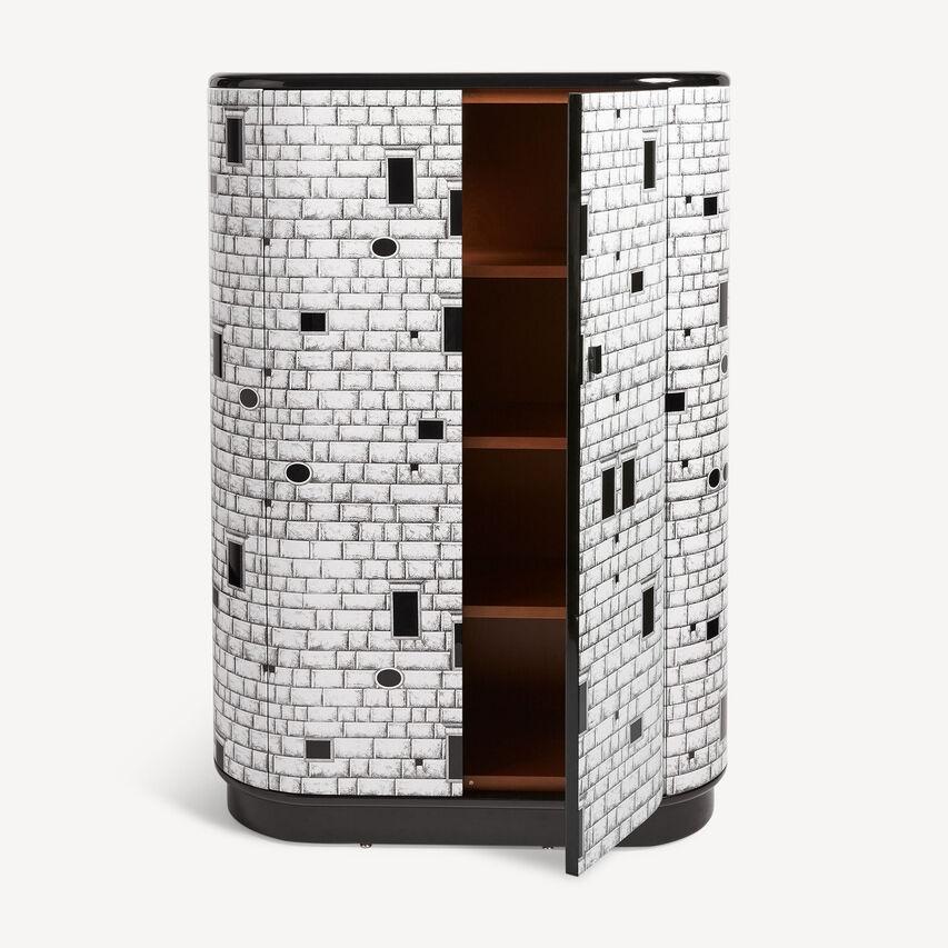 The curved cabinet shape was designed by Barnaba Fornasetti in 2003 and now it can be considered one of the most iconic pieces of furniture in the Italian atelier's collection, designed to associate its practical function as a container with an