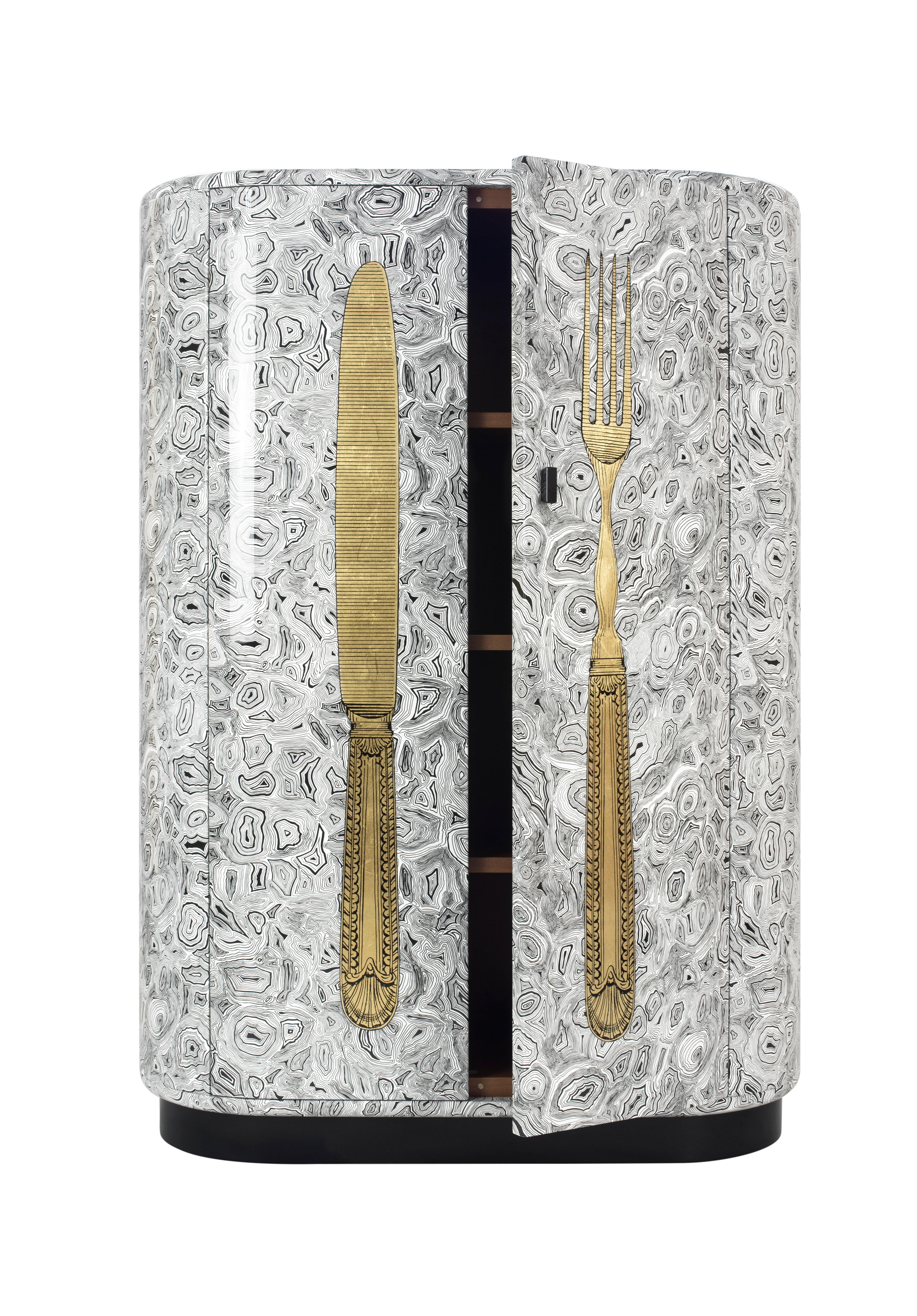 The curved cabinet shape was designed by Barnaba Fornasetti in 2003 and now it can be considered one of the most iconic pieces of furniture in the Italian atelier's collection. 

Like all Fornasetti pieces of furniture, it is handcrafted using