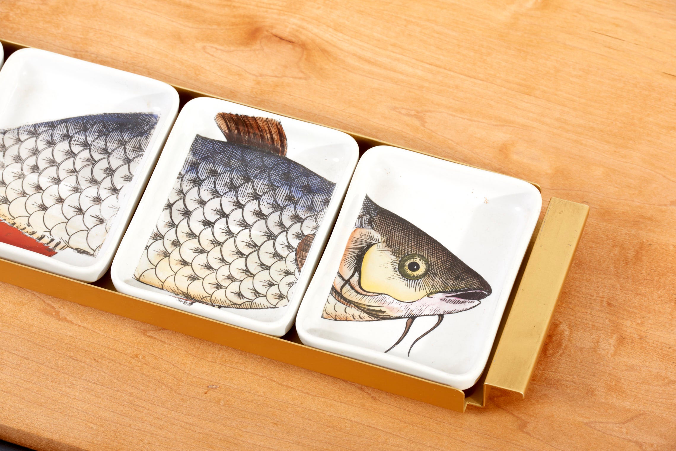 Satz von vier Fornasetti Fischschalen auf einem Tablett, Italien 1950er Jahre. Die angegebenen Maße gelten für das Tablett. Eine Schale misst 11 x 14 x 3 cm.