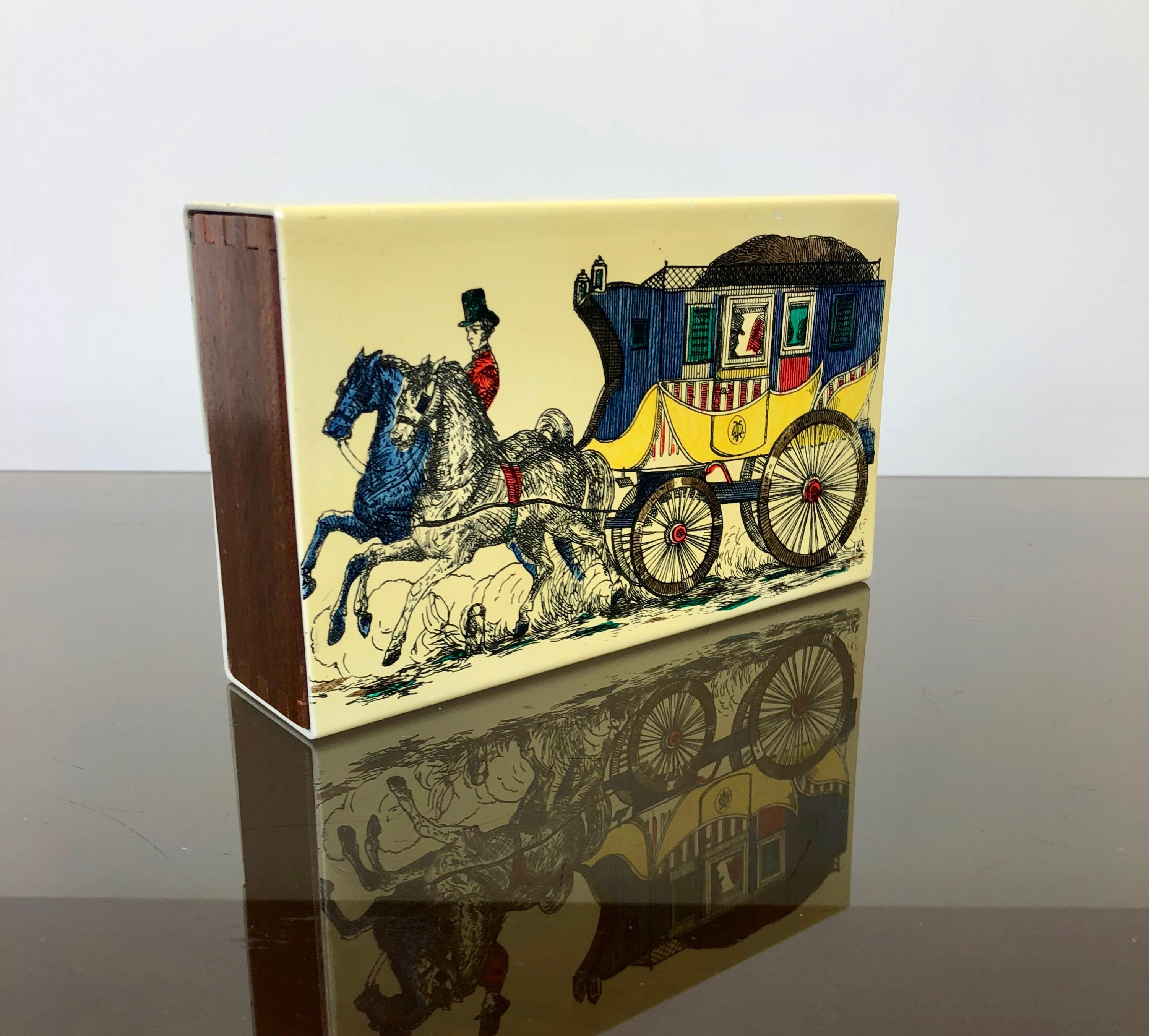 Italian Mid-Century modern card box by Fornasetti in metal wood, representing a carriage with coachmen pulled by two horses. 

This typo of artistic boxes was created to stay over time as cigarette cases, jewelry boxes, etc.