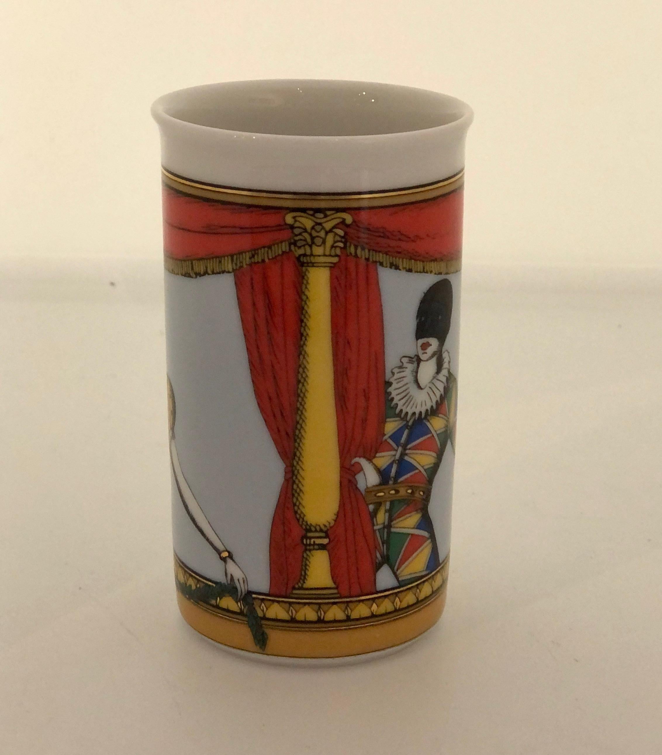 Offered is a signed Mid-Century Modern brightly colored in orange, blue, yellow, green and black court jester themed petite white porcelain vase or pencil holder by Fornasetti for Rosenthal. The court jester theme and vibrant colors bring