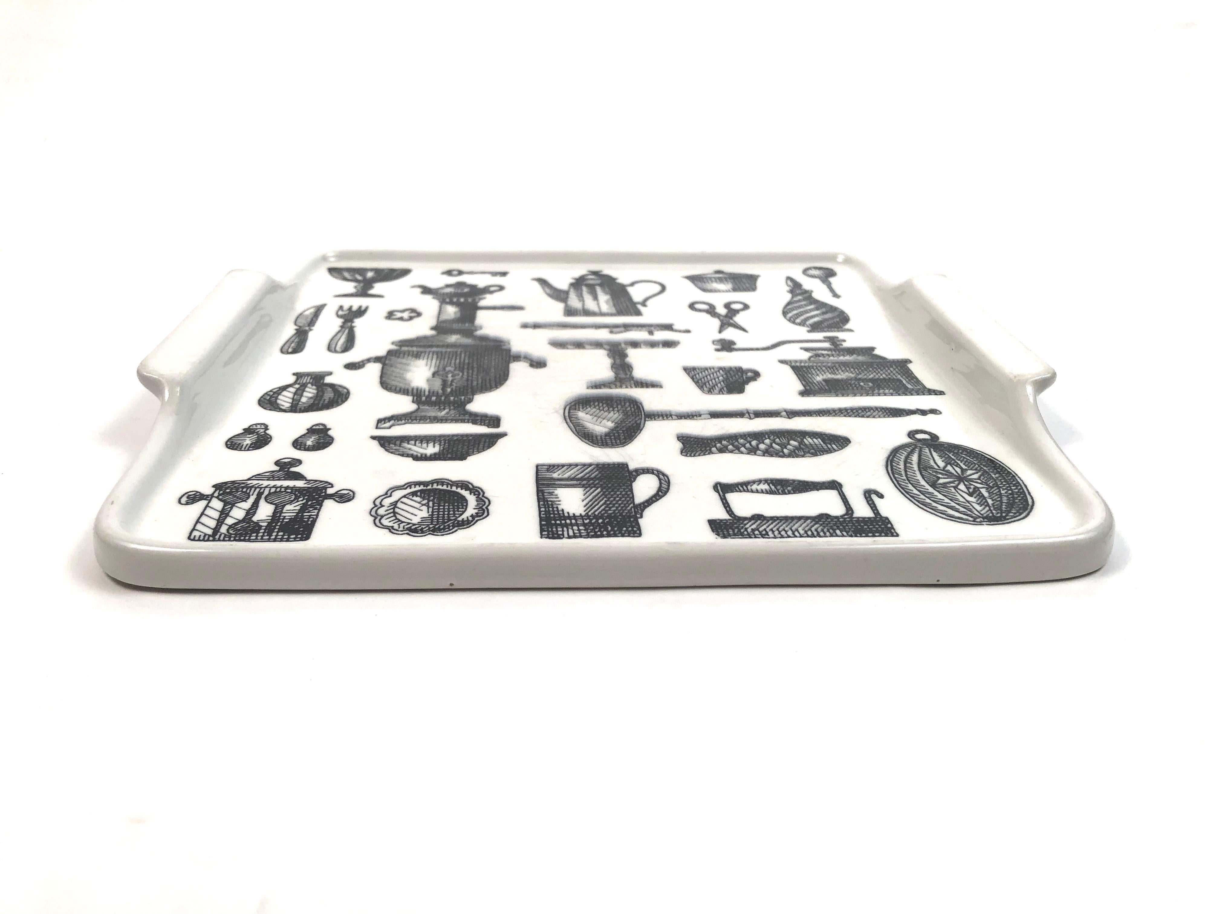 A vintage square ceramic tray by Arabia of Finland, decorated with black and white transferware illustrations, of kitchenware, including a coffee pot and grinder, tea urn, ladle, cake stand, cutlery, pudding mold, salt and pepper Shaker, among