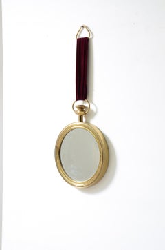 Specchio in ottone in stile Fornasetti con nastro di velluto rosso cardinale.