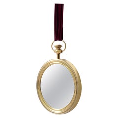 Specchio in ottone in stile Fornasetti con nastro di velluto rosso cardinale.