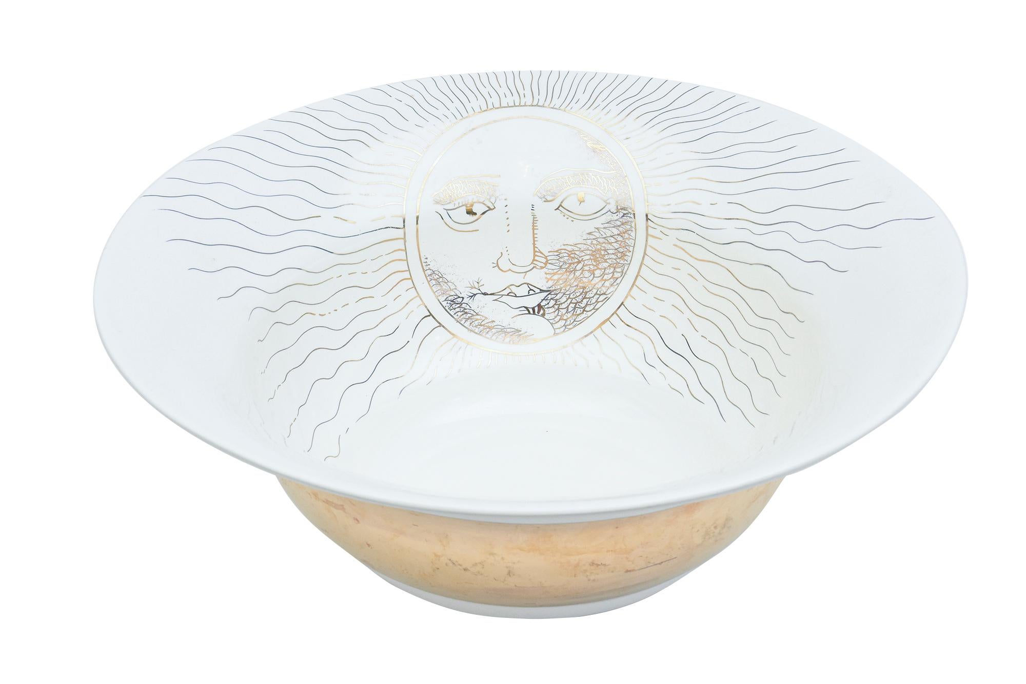This very large ceramic bowl has the influence of Piero Fornasetti in the sun motif face.
It is signed on the bottom Laurie Gatea Los Angeles Pottery. From the 90's.
The gold banding surrounds the exterior. It must be hand washed.