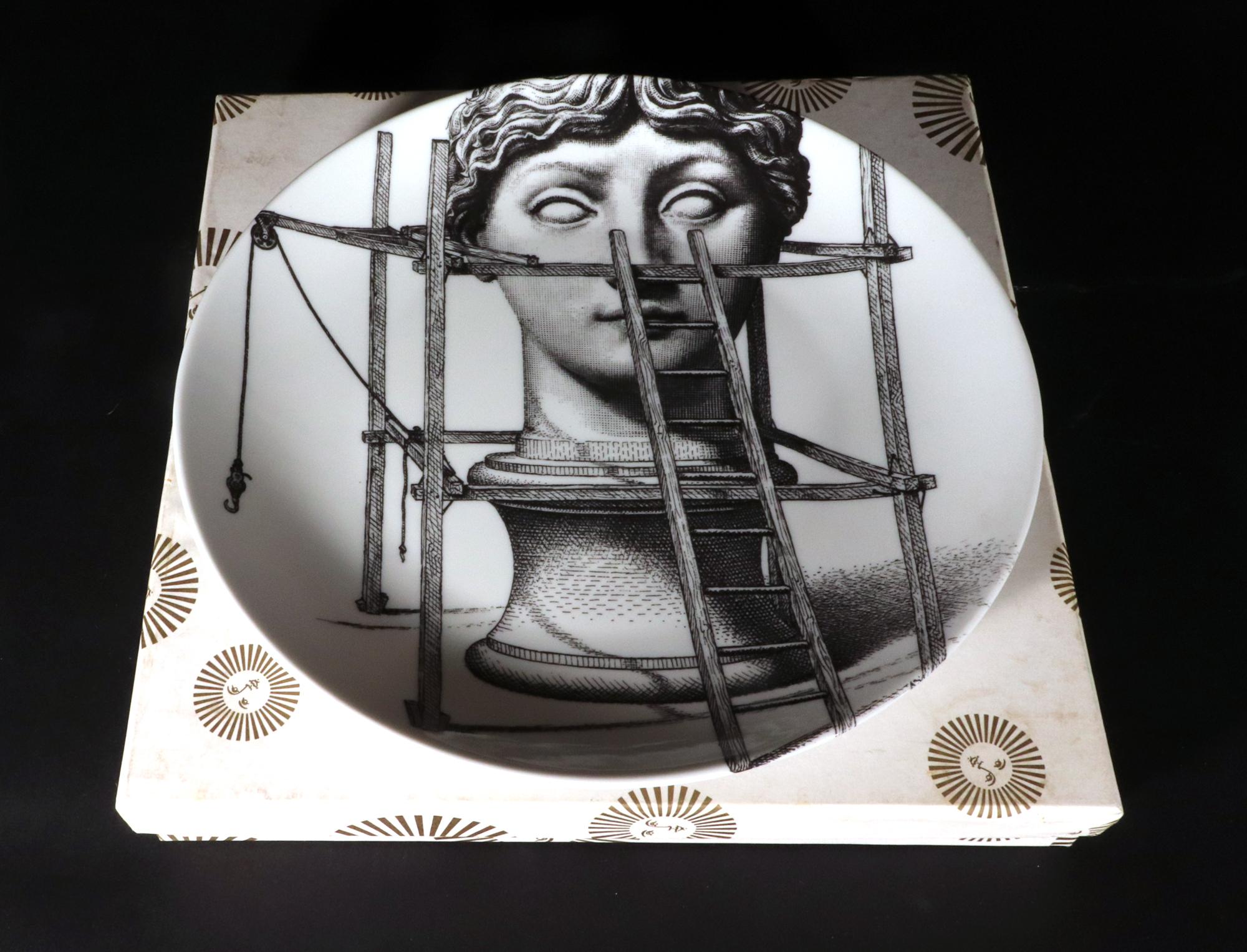 Fornasetti Themes & Variation Porcelain Plate with Original White Box, 
Number 200,
The Statue,
1990s

The Fornasetti porcelain plate is number 200 in the Themes & Variation series.  The image shows a giant neoclassical bust of a woman on a plinth