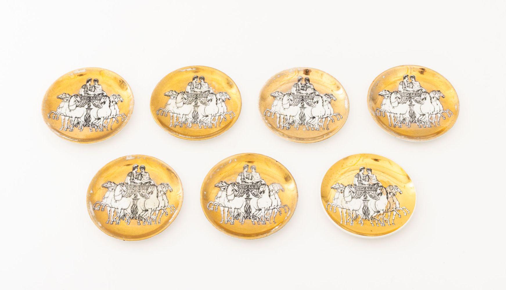 Ensemble de huit pièces de vaisselle en porcelaine Piero Fornasetti pour Saks Fifth Avenue, comprenant : (7) sept sous-verres et (1) un cendrier, à fond doré, marqué 