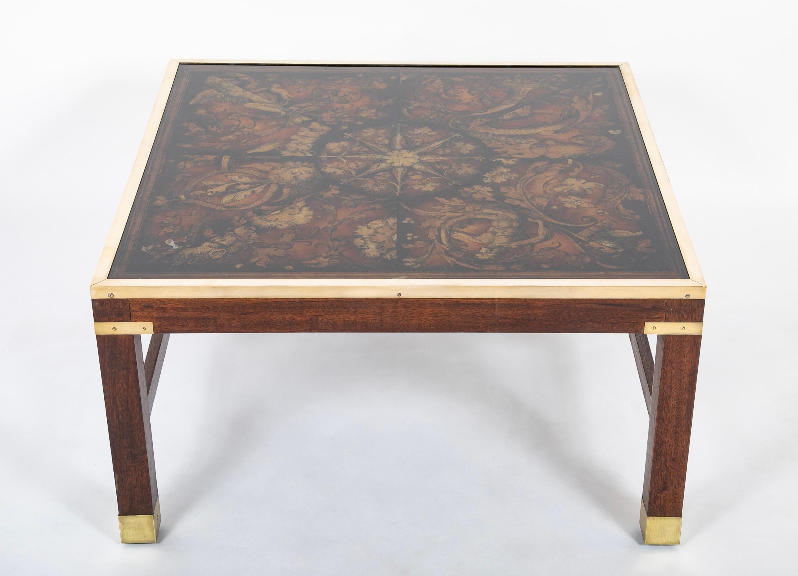 A very interesting mid-20th century Fornesetti style glass top coffee table on a walnut base with brass mounts and border. Unusual and intriguing reverse printed glass top with acanthus leaves and mythological figures radiating out of a compass like