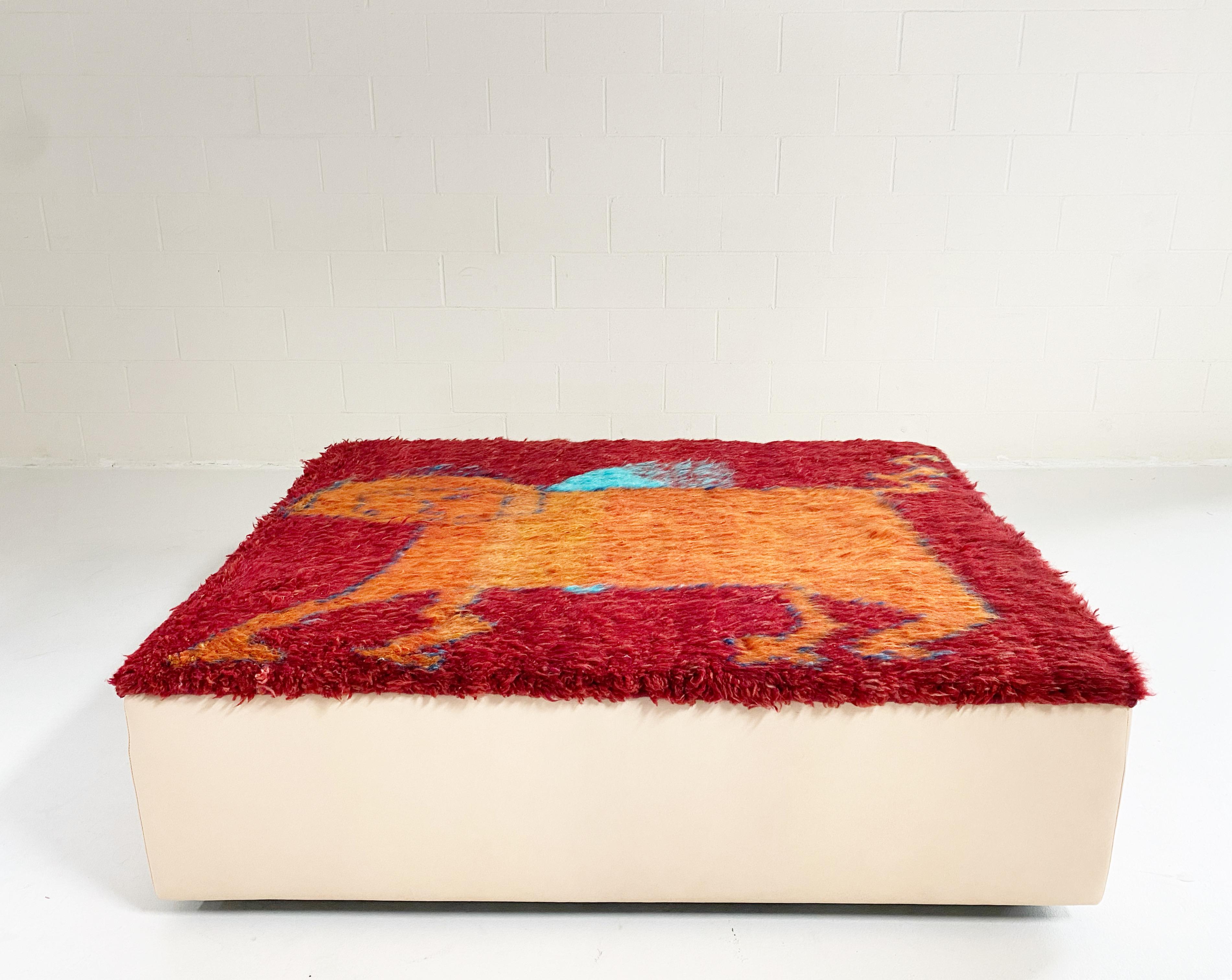 A one-of-a-kind ottoman designed by Forsyth and beautifully handmade using a vintage Iranian gabbeh rug (100% hand-spun sheep wool). The rug is finished with luxurious vegetable tanned leather sides. The perfect coffee table, ottoman, or extra