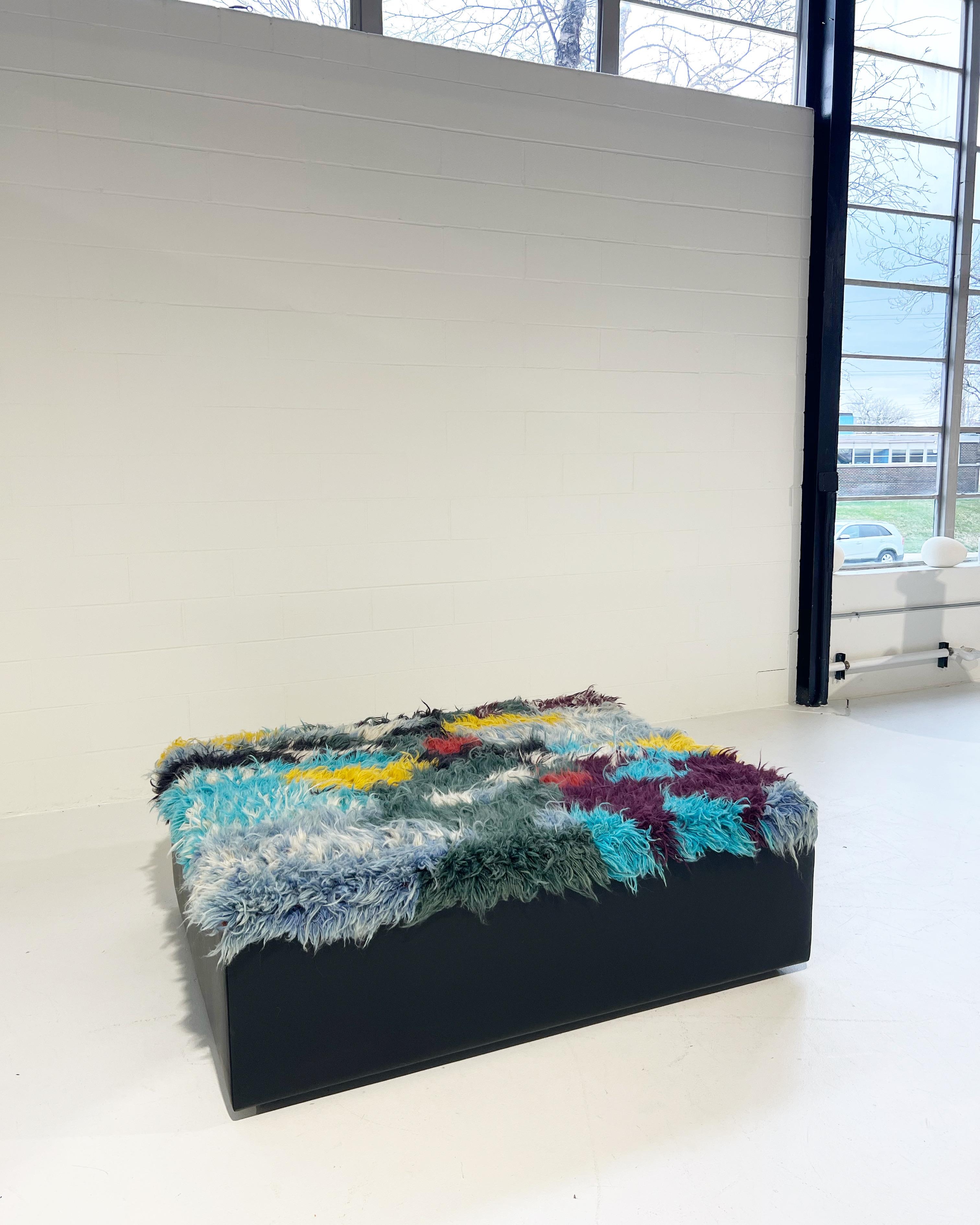 A one-of-a-kind ottoman designed by Forsyth and beautifully handmade using a vintage Iranian gabbeh rug (100% hand-spun sheep wool). The rug is finished with luxurious leather sides. The perfect coffee table, ottoman, or extra seating.
