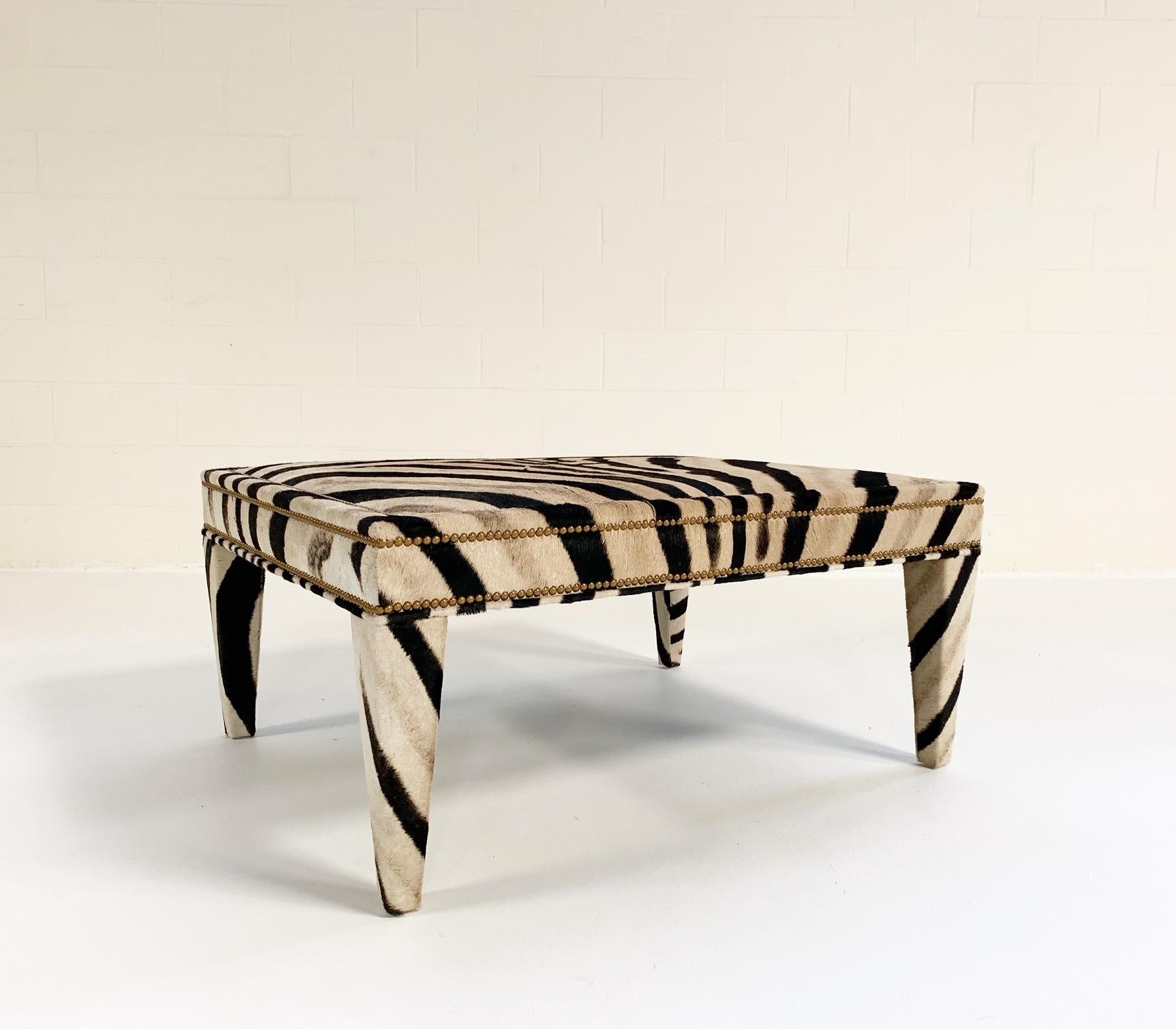 A Forsyth signature item, this zebra hide ottoman can double as a chic and elegant coffee table. Custom made to order in the Forsyth studio, the zebra hide is masterfully wrapped around a wooden frame and expertly finished with brass nailheads. Each