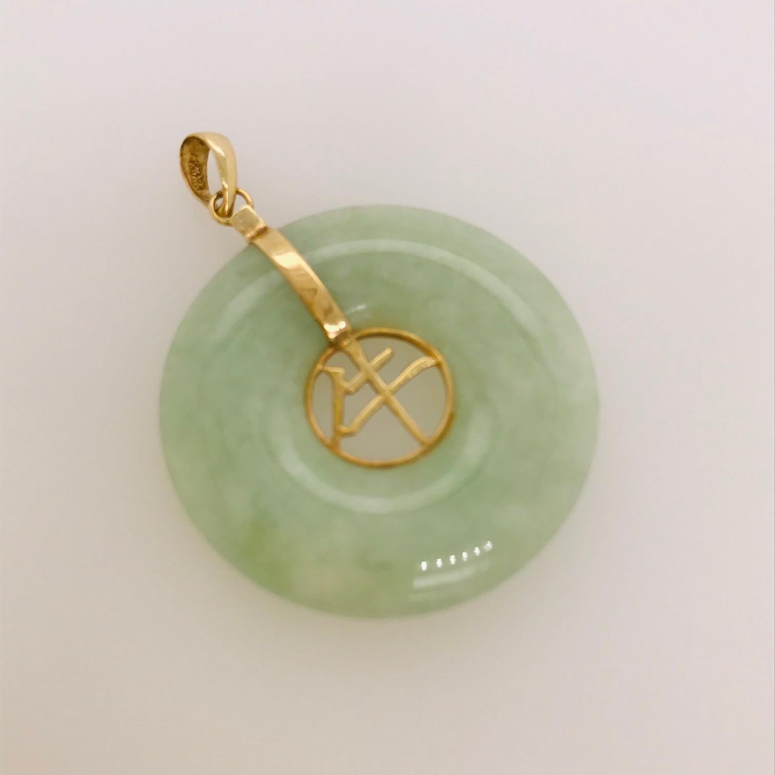This gorgeous genuine jade piece is special and unique. A genuine jade disk that is help in a 14k yellow gold casing that attached to a complimentary yellow gold bail. The jade has a beautiful Chinese symbol in the open space that has been hand