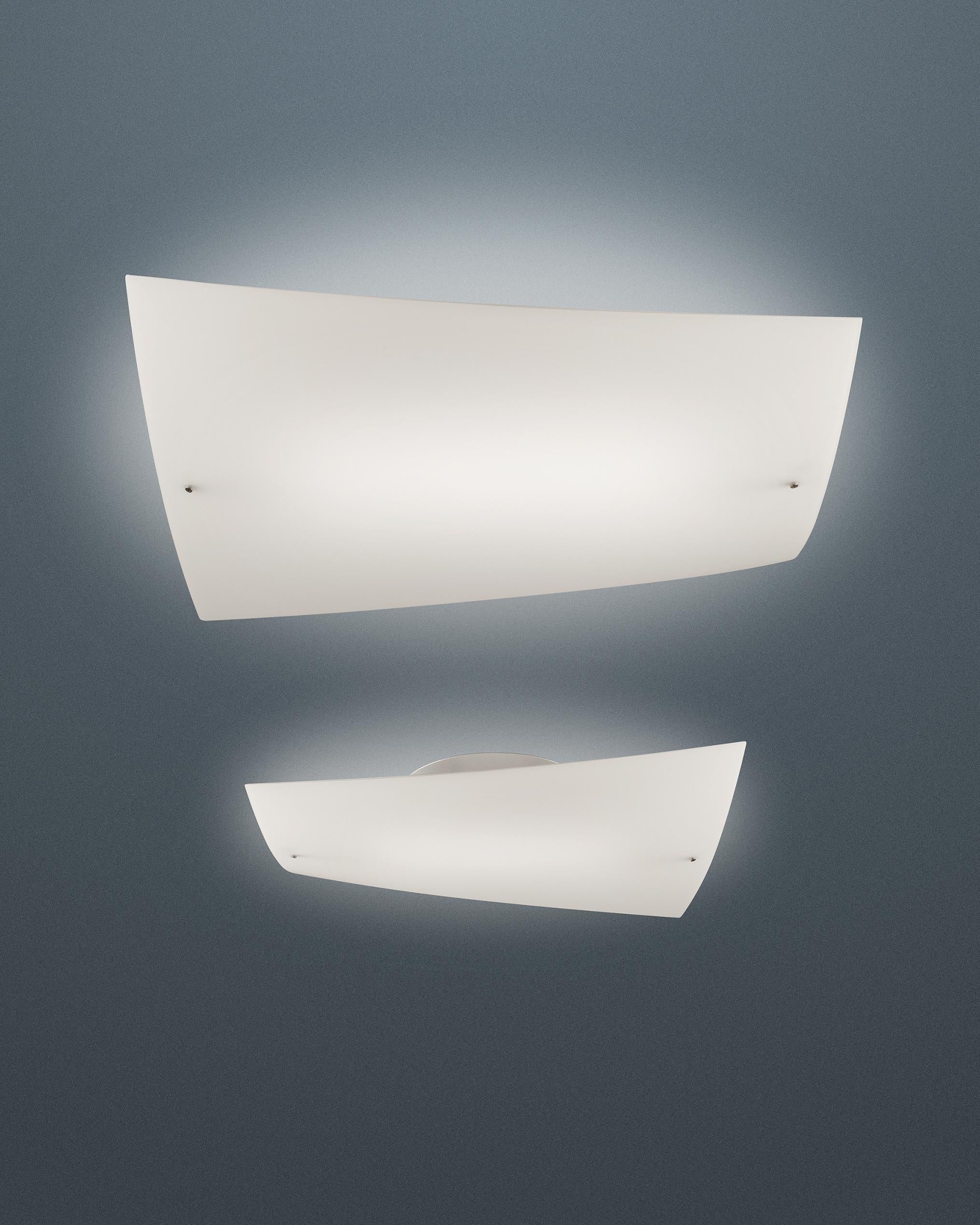 Lampada da parete con luce riflessa e diffusa. Diffusore in vetro incamiciato soffiato a mano, piegato a caldo e sottoposto esternamente a immersione in acido. Piastra di montaggio a parete che ospita la parte illuminotecnica, realizzata in