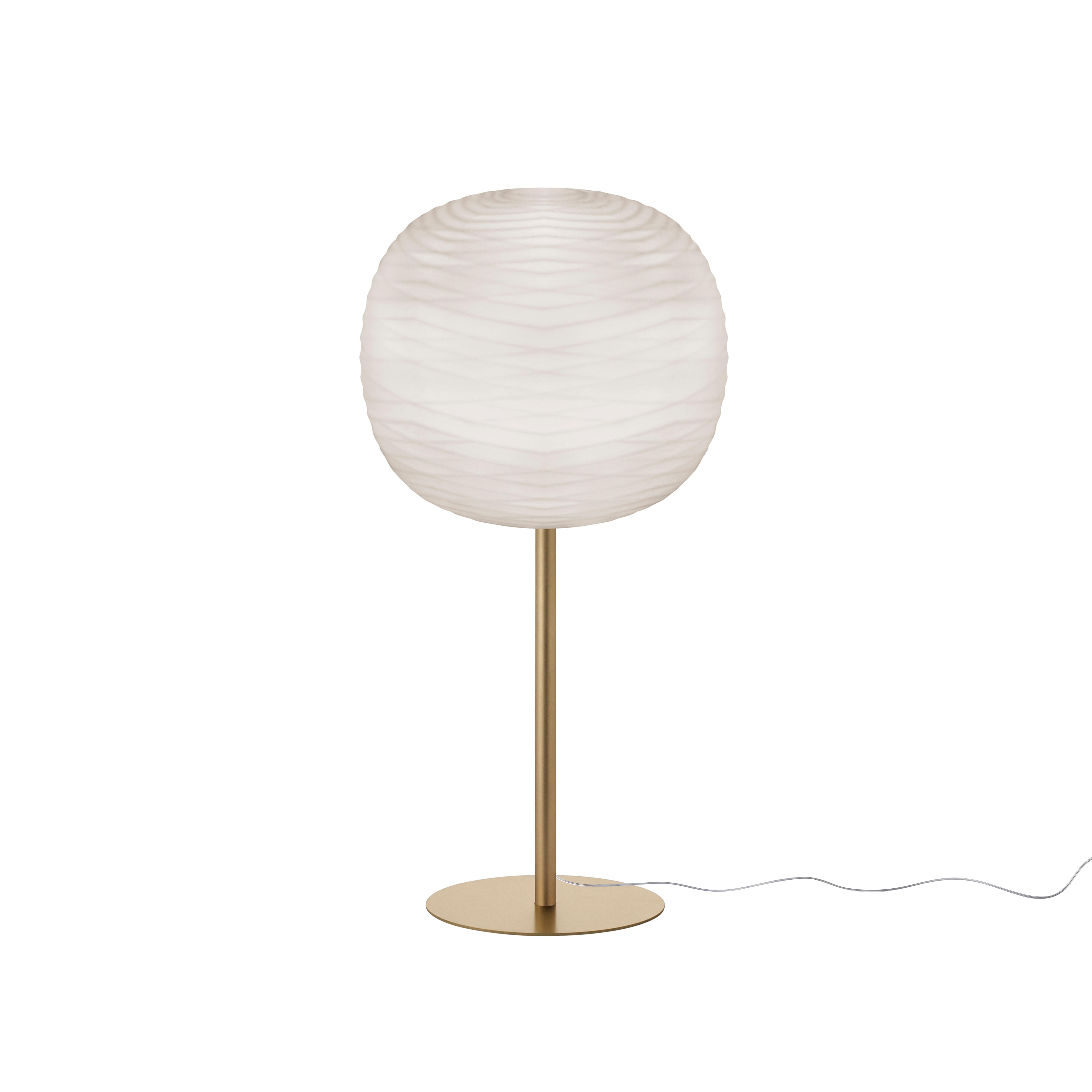 A fluid vibration on glass. The Gem table lamp is a seductive object that declares at first glance the superior value of the material and the fine craftsmanship of its manufacturing process. Unmistakable even when it is switched off, it has a satin