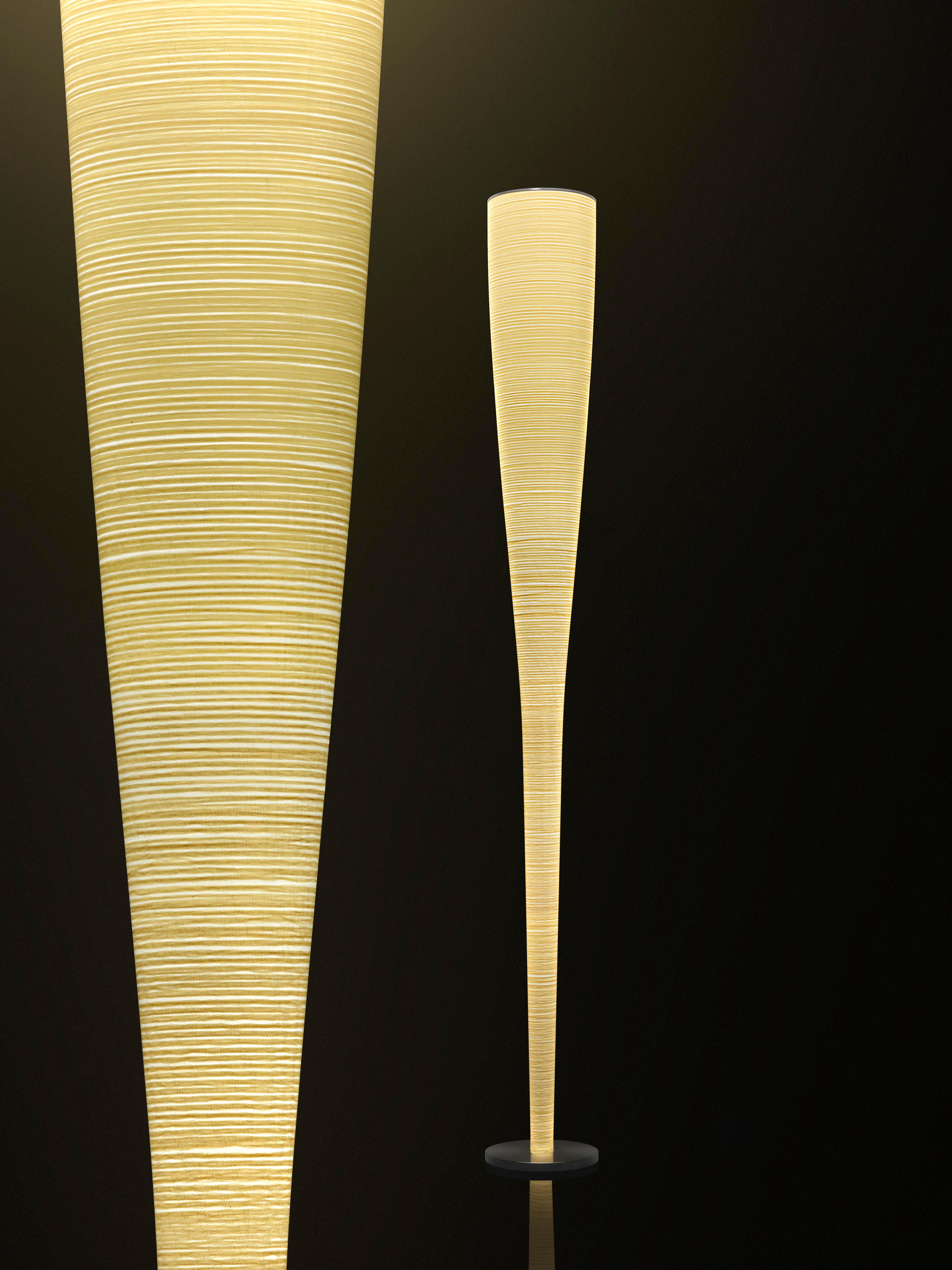 Floor lamp with diffused and indirect light. Diffuser achieved using an artisanal process that entails the application of a Kevlar® thread for the yellow version and a carbon thread for the black version onto a glass fabric. Internal metal rod; the