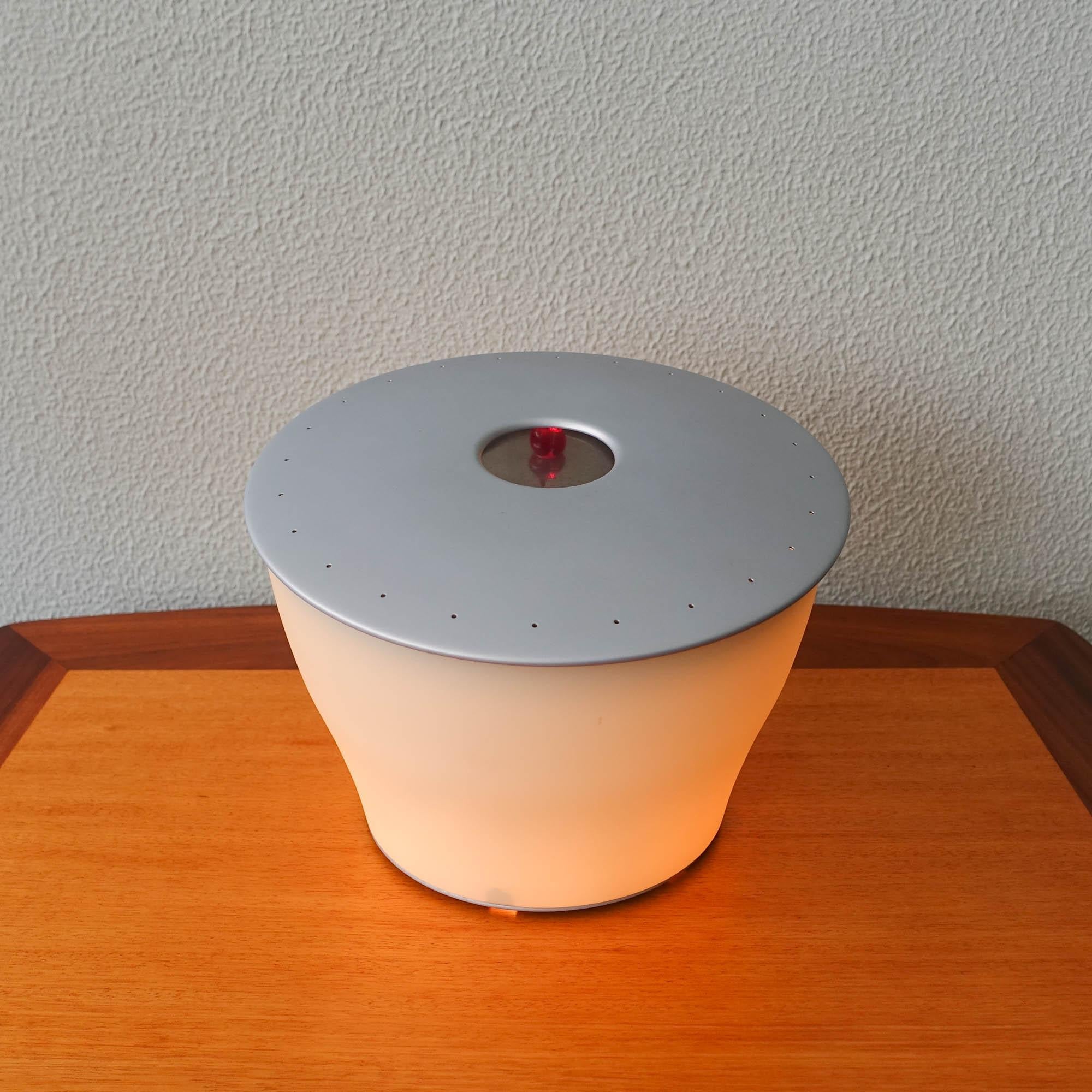 This table lamp, model Elfo, was designed by Denis Santachiara and produced by Foscarini, in Italy in 1999. It is made with blown satin glass diffuser, white inside and coloured outside and lacquered metal disc. Features mirrored reflectors that
