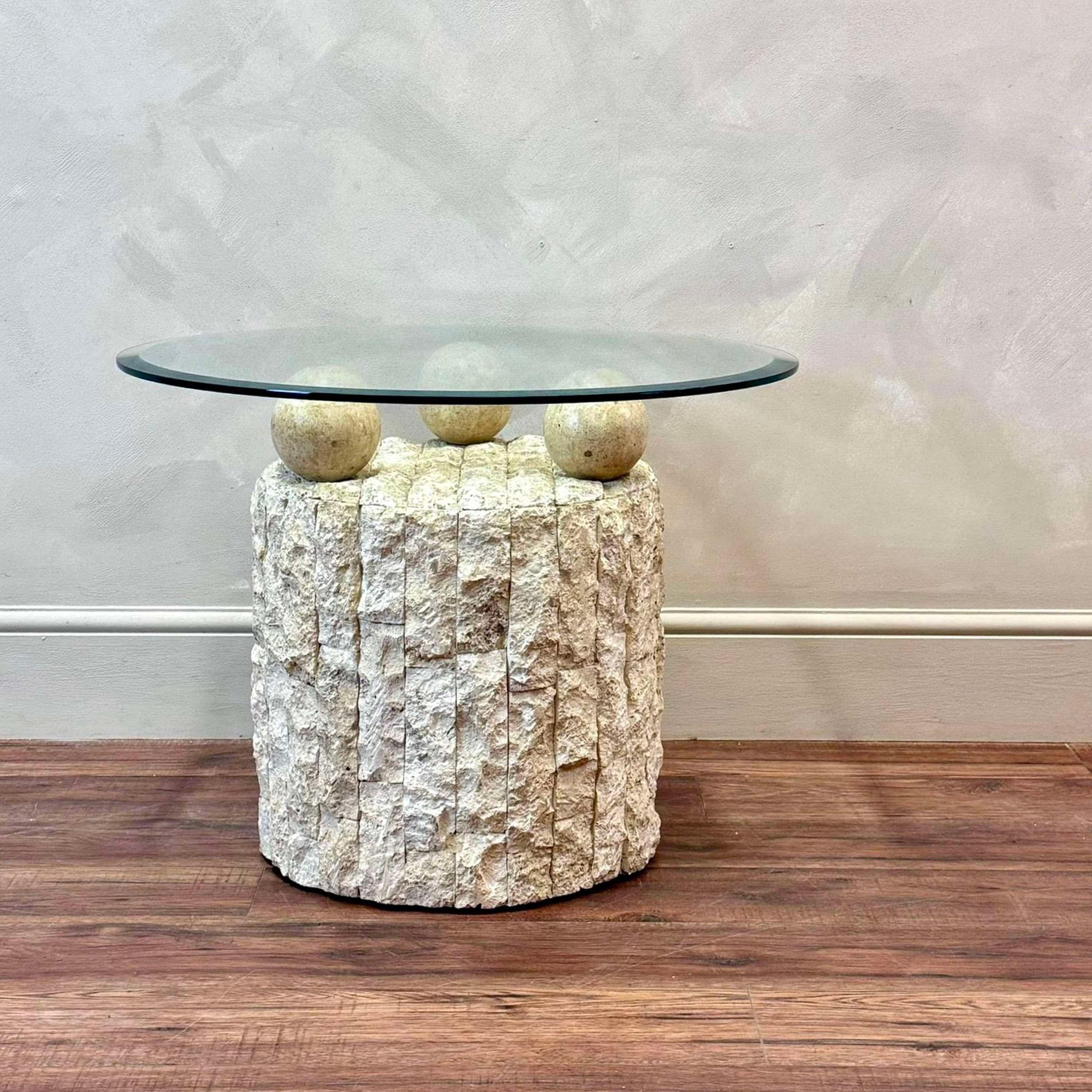 Postmodern design, coffee / side table by Magnusse Ponte. 
The base made from Mactan stone.
Three stone balls hold the removable, bevel edged round glass top.

Circa 1980.

Dimensions:H: 53.5cm (21.1