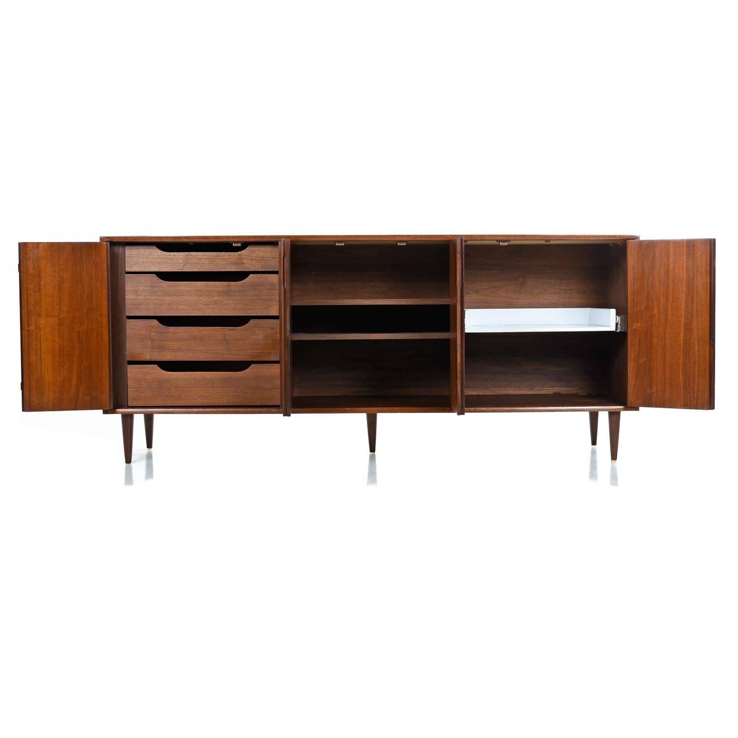 Restored Mid-Century Modern American made walnut credenza. The simple design is intriguing in the way that it balances modern and traditional themes. The exceptional length is the perfect dimension for your flat screen TV if you choose to use this
