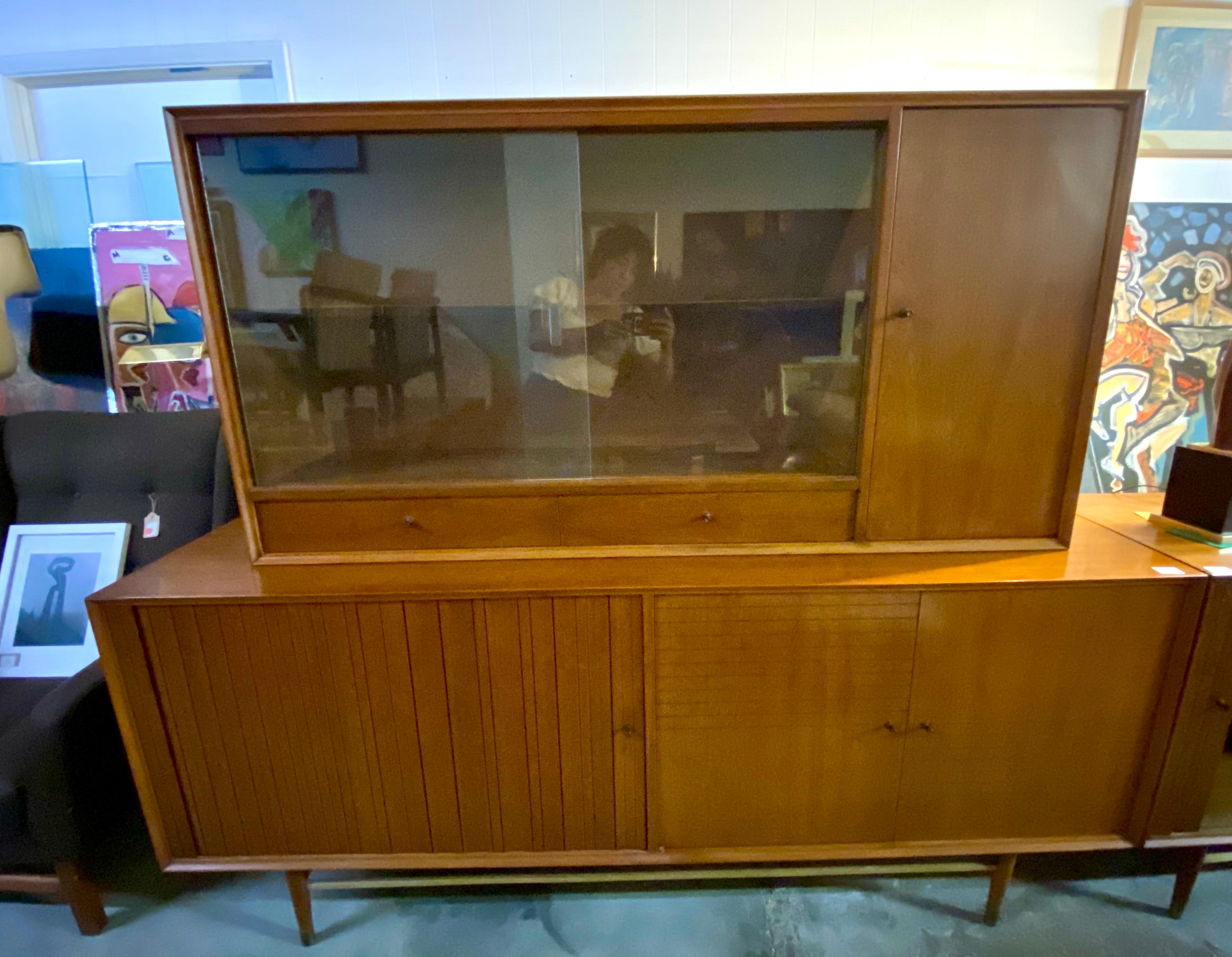 Vintage walnut credenza / sideboard by Foster-McDavid features a hutch and plenty of storage. The left side of credenza has a sliding tambour door with two shelves and the right side opens up to three shelves. The Hutch features glass sliding doors