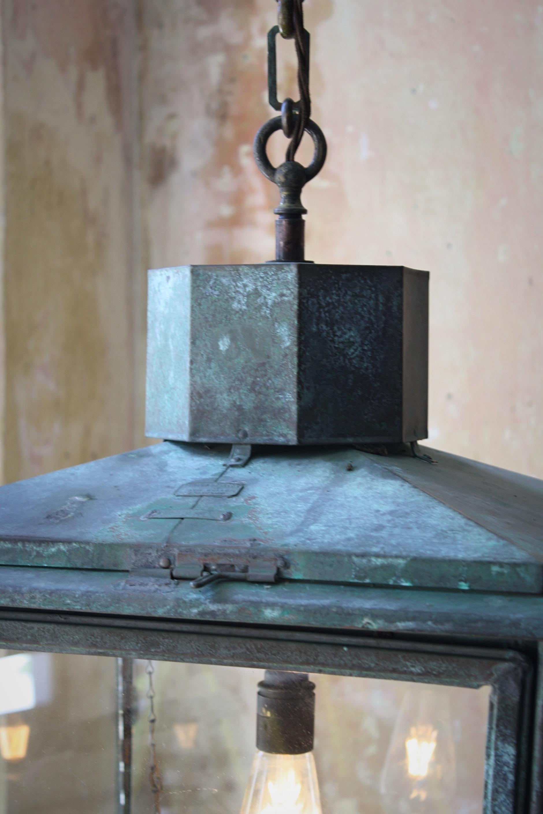 A large and unusual square lantern by Foster & Pullen of Bedford England.

Glazed and sheet copper hanging lantern with a natural verdigris finish.

Early 20th century in age 

Age related wear, marks, dings and dents but in overall excellence