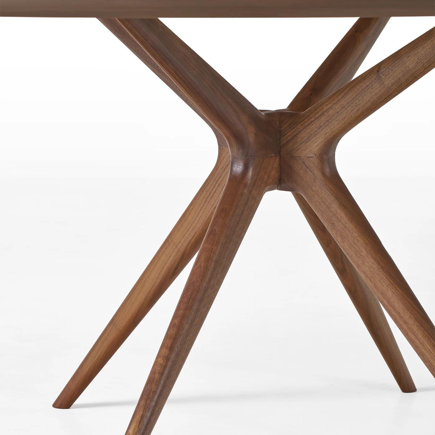 This 180 cm round dining table showcases a striking herringbone-patterned top, treated with an oil-based protective finish for enhanced scratch resistance. Its solid walnut base features a sculptural, contemporary design that offers both stability