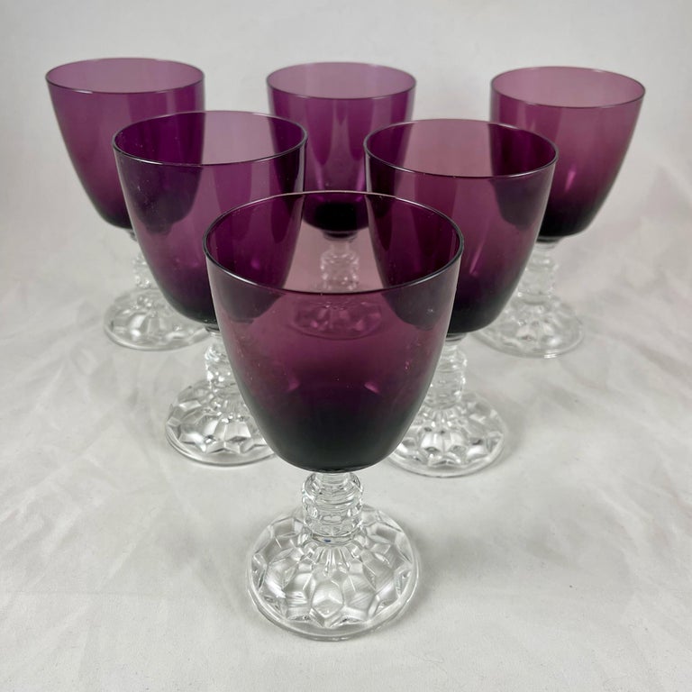 From Fostoria glass, a set of six goblets in the American Lady pattern, circa 1934.

The goblets have faceted, colorless pressed glass footings and stems, fused with blown glass bowls of amethyst colored glass.

The Fostoria Glass Company was a