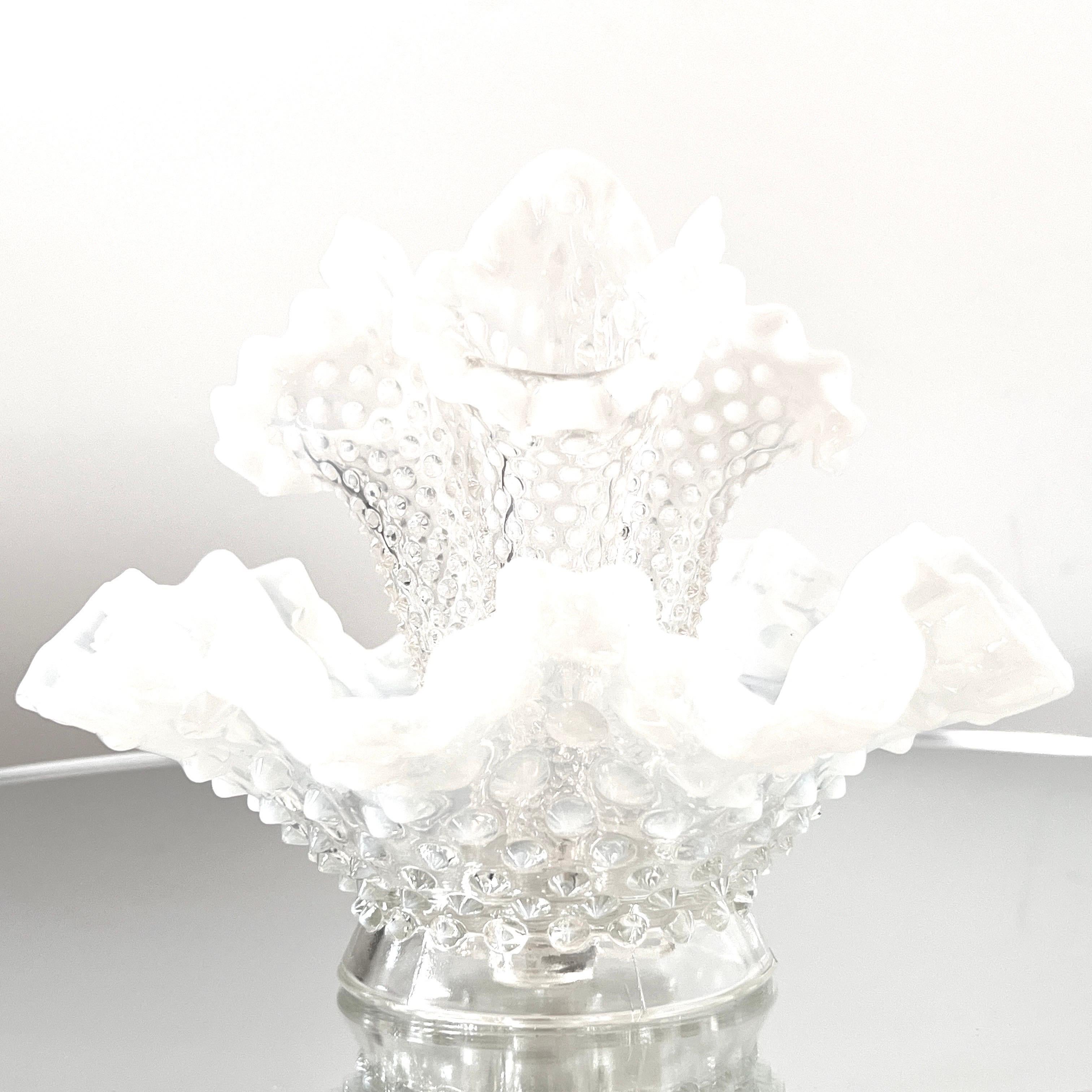 Inspired by Victorian Era design, this vintage epergne vase is fitted with three central bud vases. The bud vases have floral forms with removable stems that feature clear diamond point glass and white opaline hobnails. The bowl features a floral