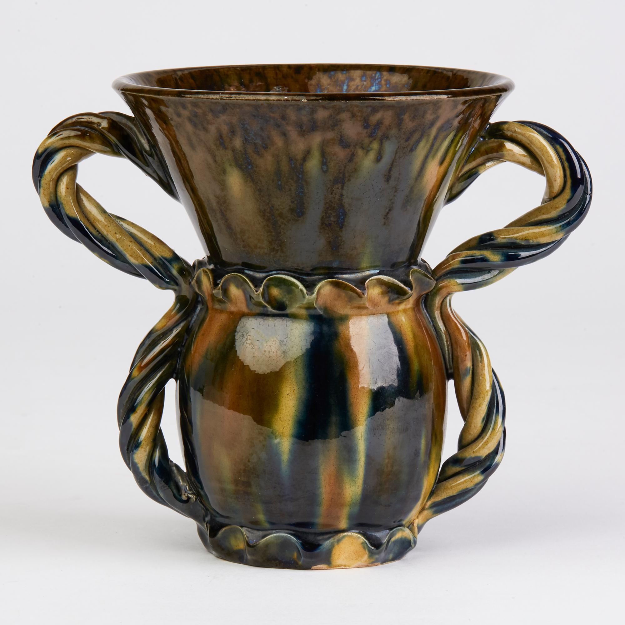 An unusual and exceptional antique French Vallauris twin handled art pottery vase attributed to Foucard-Jourdan decorated with blue, brown, yellow and green streaked glazes and applied with a double loop rope twist handle dating from the early 20th