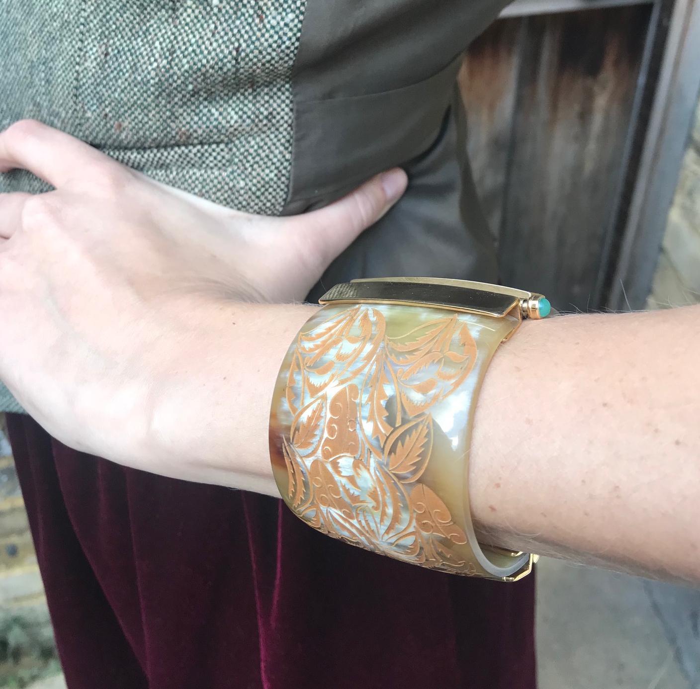 Cuff bracelet made of African cow horn engraved with wild foliage motif. The intricate pin-clasp is set with a choice of fire opal or emerald, sourced from conflict-free mines in Africa. 

Hand crafted by artisans in Kenya, East Africa and finished