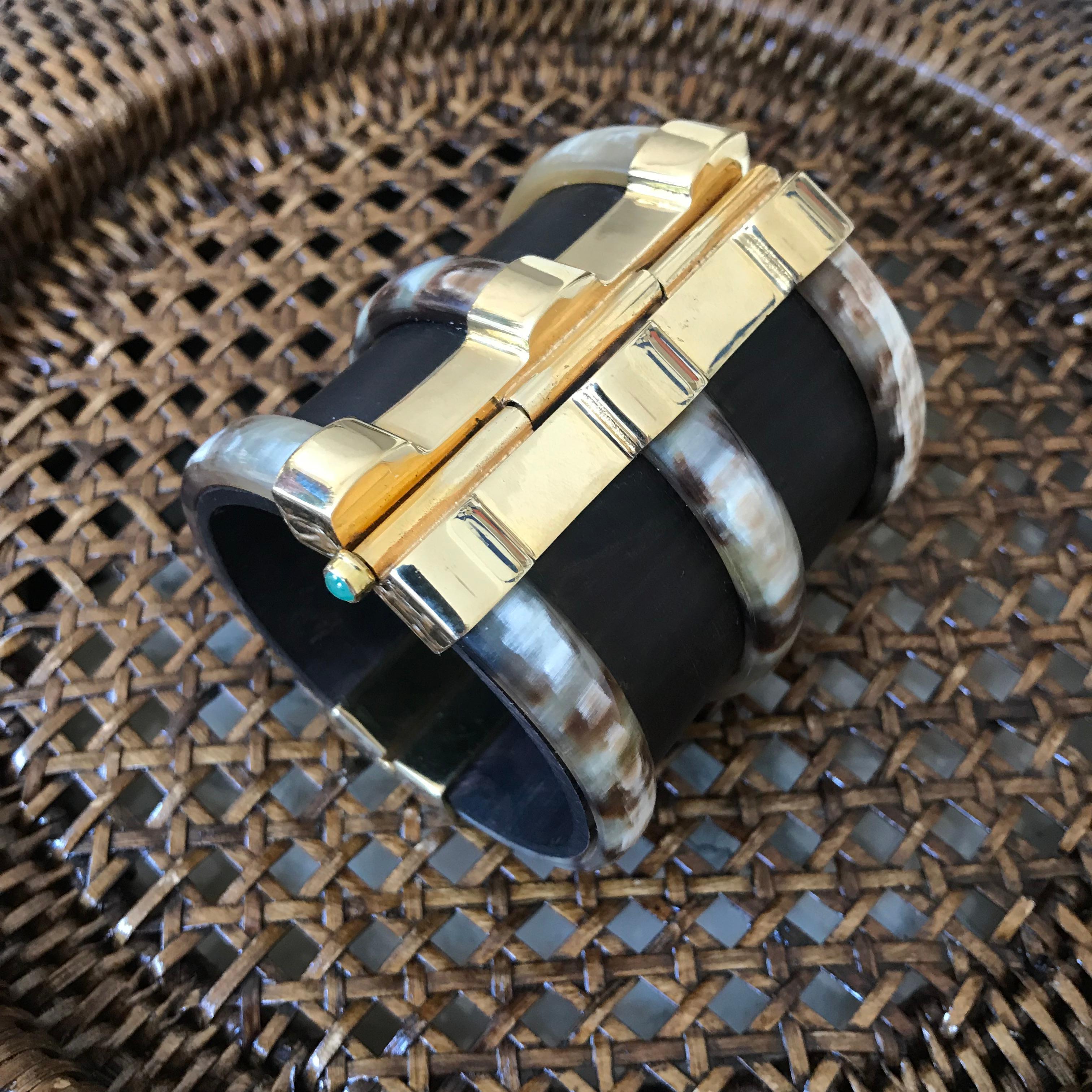 Cuff bracelet crafted by hand from ebony wood and African cow horn. The intricate plate pin-clasp is set with a emerald. Inspired by warrior style cuffs worn by former Vogue editor Diana Vreeland. 

Hand crafted by artisans in Kenya, East Africa and