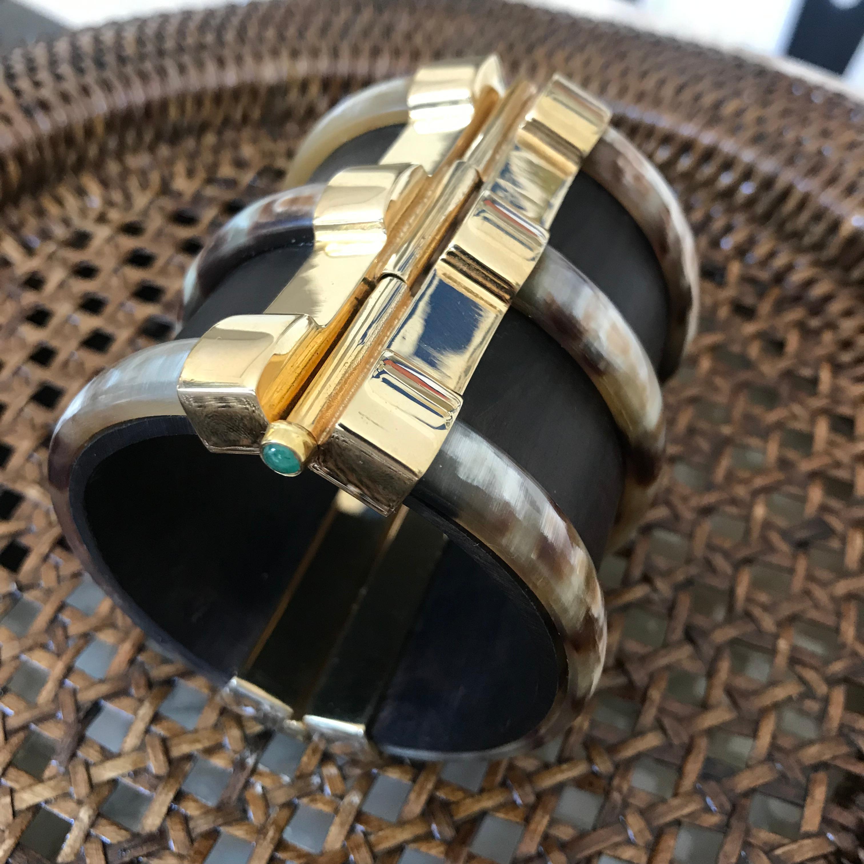 Cuff bracelet crafted by hand from ebony wood and African cow horn. The plate pin-clasp is set with an emerald. Inspired by warrior style cuffs worn by former Vogue editor Diana Vreeland. 

Hand crafted by artisans in Kenya, East Africa and finished