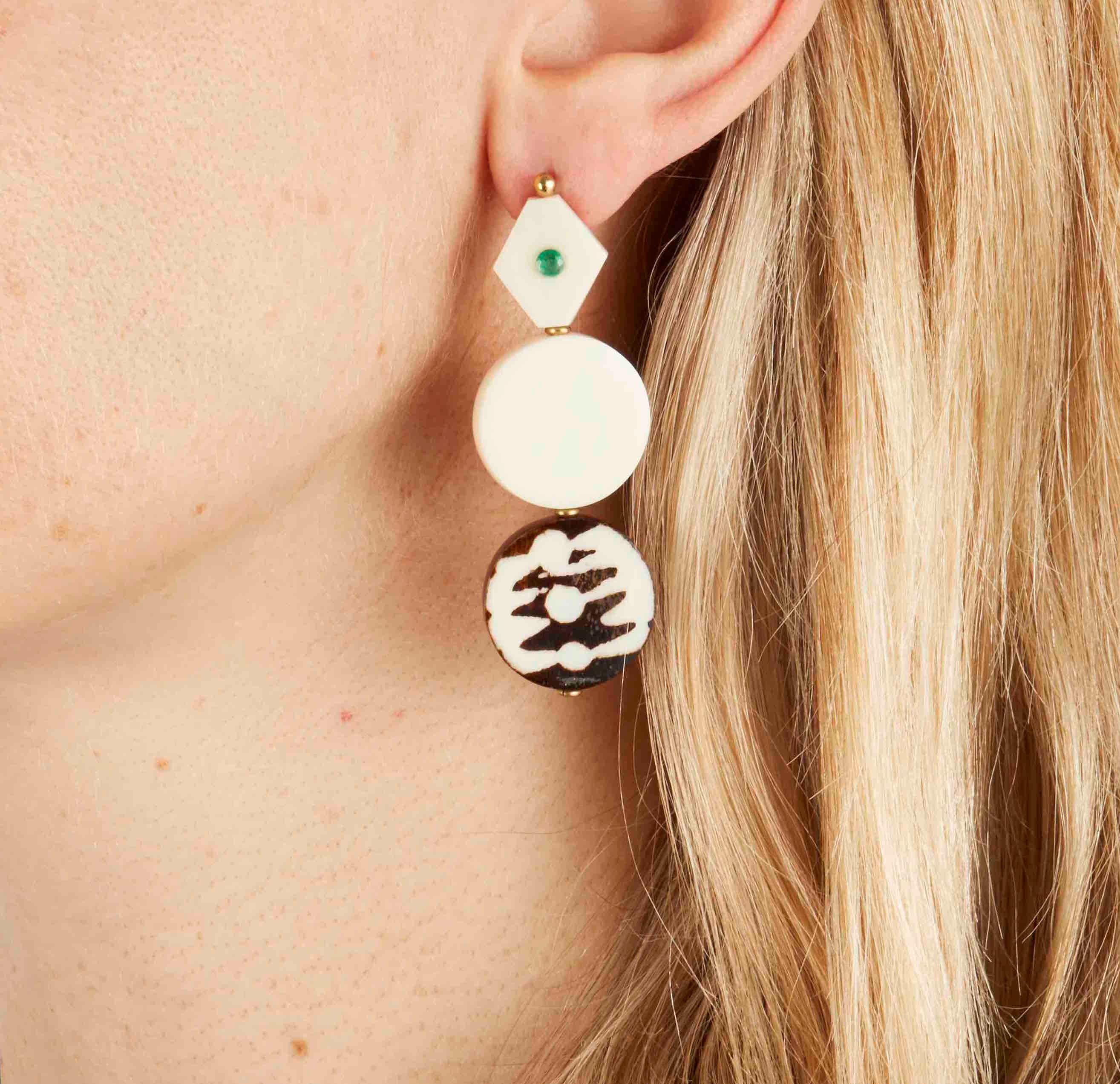 The finest carved African camel bone earrings handmade in London using solid brass with solid silver pin-backs, set with African emerald. These earrings feature a batik design process ancient to Kenyan tribes.

The camel bone is hand carved by