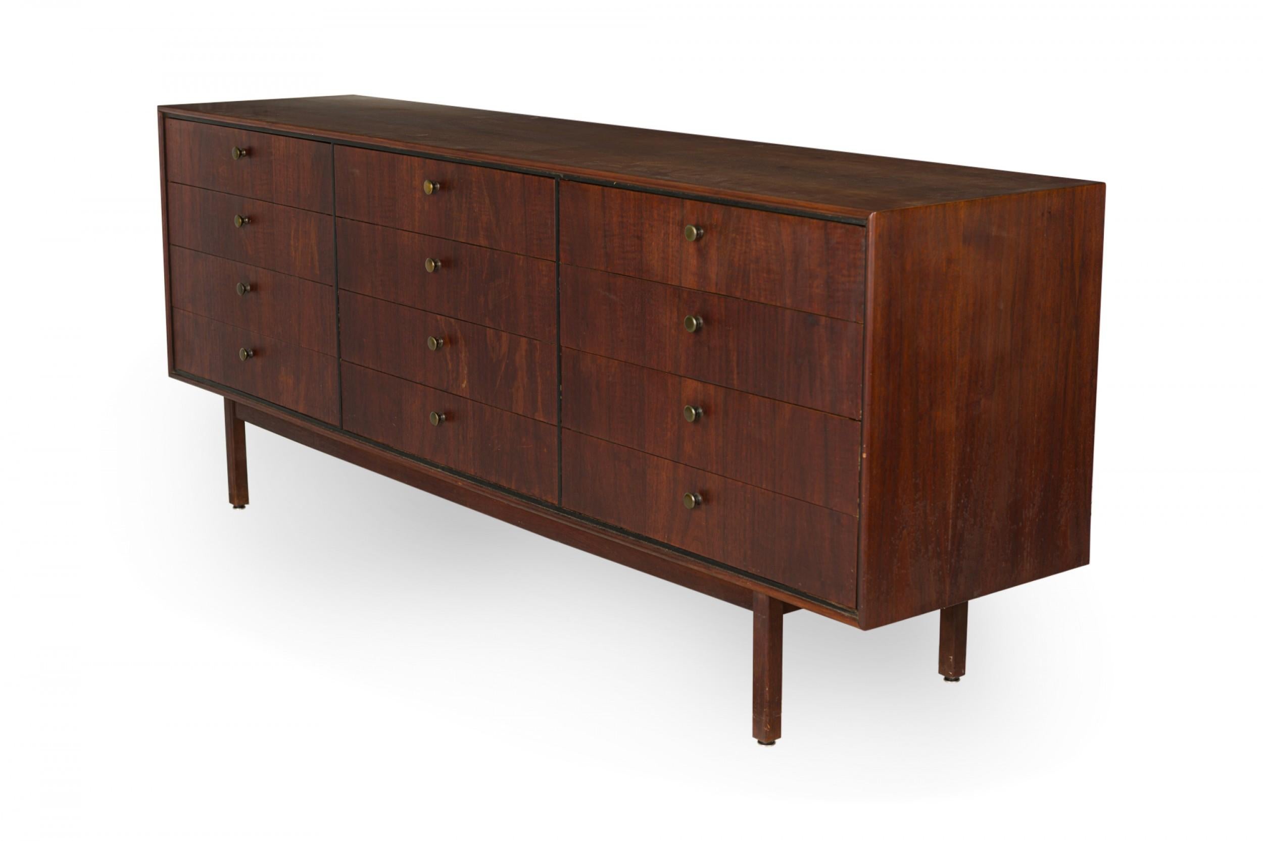 American Mid-Century teak 12-drawer low chest with three sections of four drawers each with circular brass drawer pulls in a rectangular cabinet resting on four square teak legs. (FOUNDERS / DILLINGHAM FURNITURE).