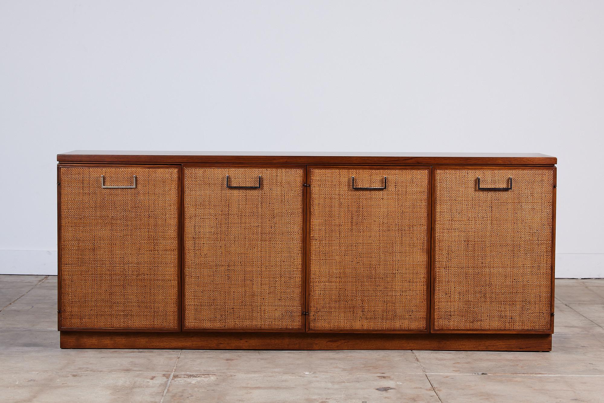 Founders four door walnut cane front credenza, c.1970s, USA. This piece features four beautiful cane front door panels and angular chrome door pulls. The interior allows for ample storage with two drawers along the top of the credenza and four