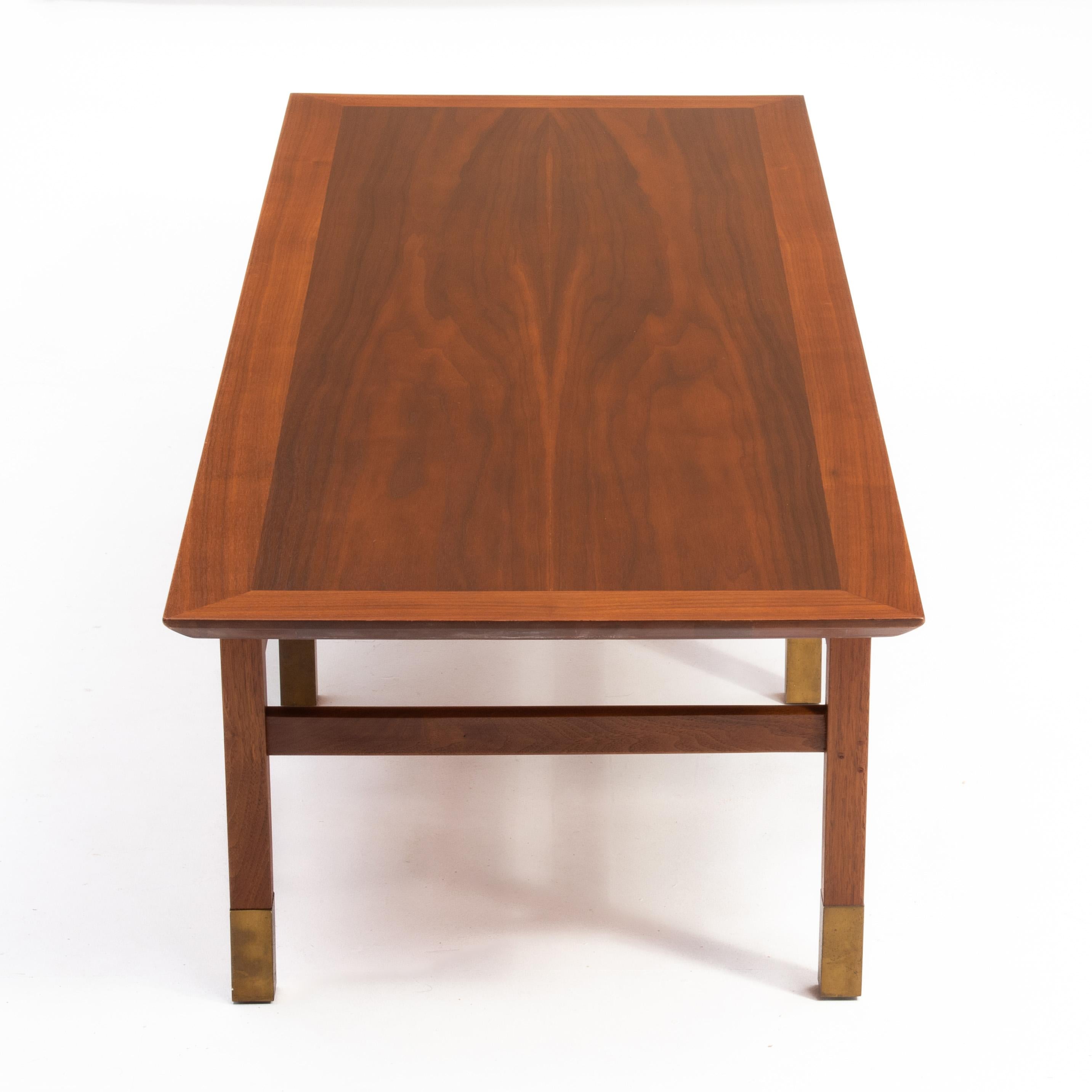 An unmarked Founders Furniture Mid Century walnut coffee table. The table features a framed book matched top and six brass capped legs. Extremely well made and unmarked as most Founders pieces are.