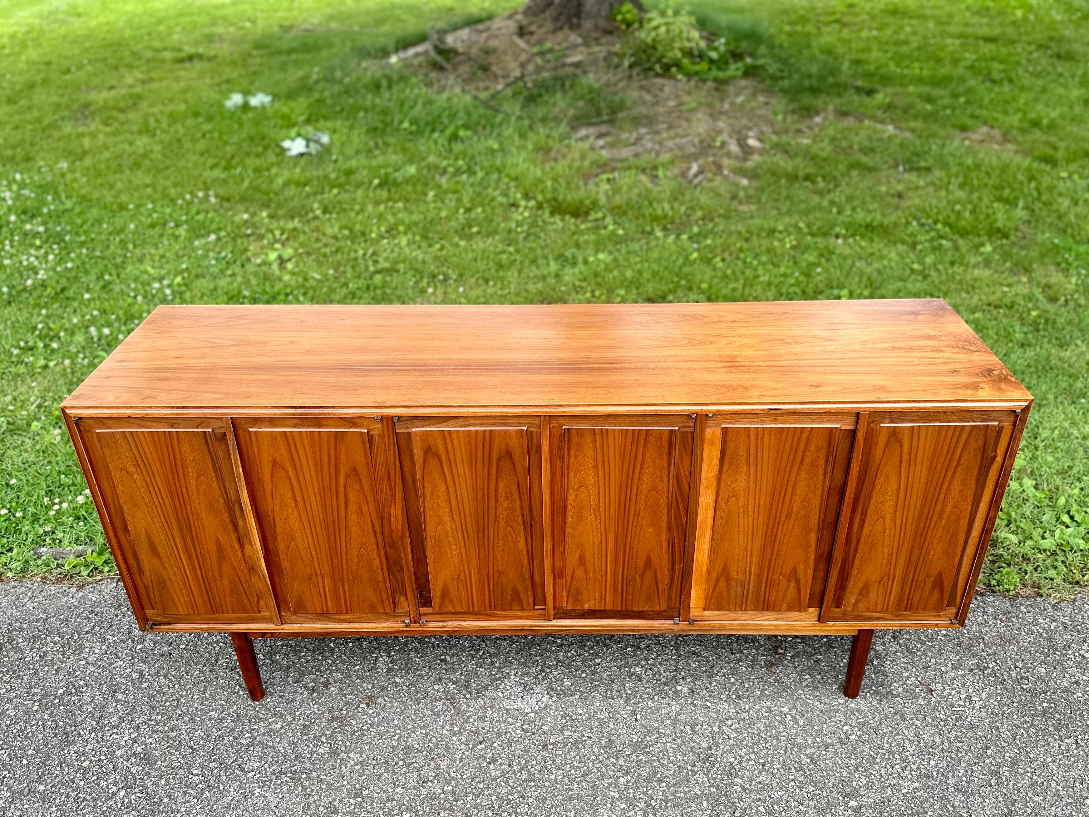Beautiful mid-century modern credenza designed by Jack Cartwright for Founders. Sleek and functional with ample storage. Amazing walnut wood grain throughout. Credenza has been professionally restored to its original beauty. 