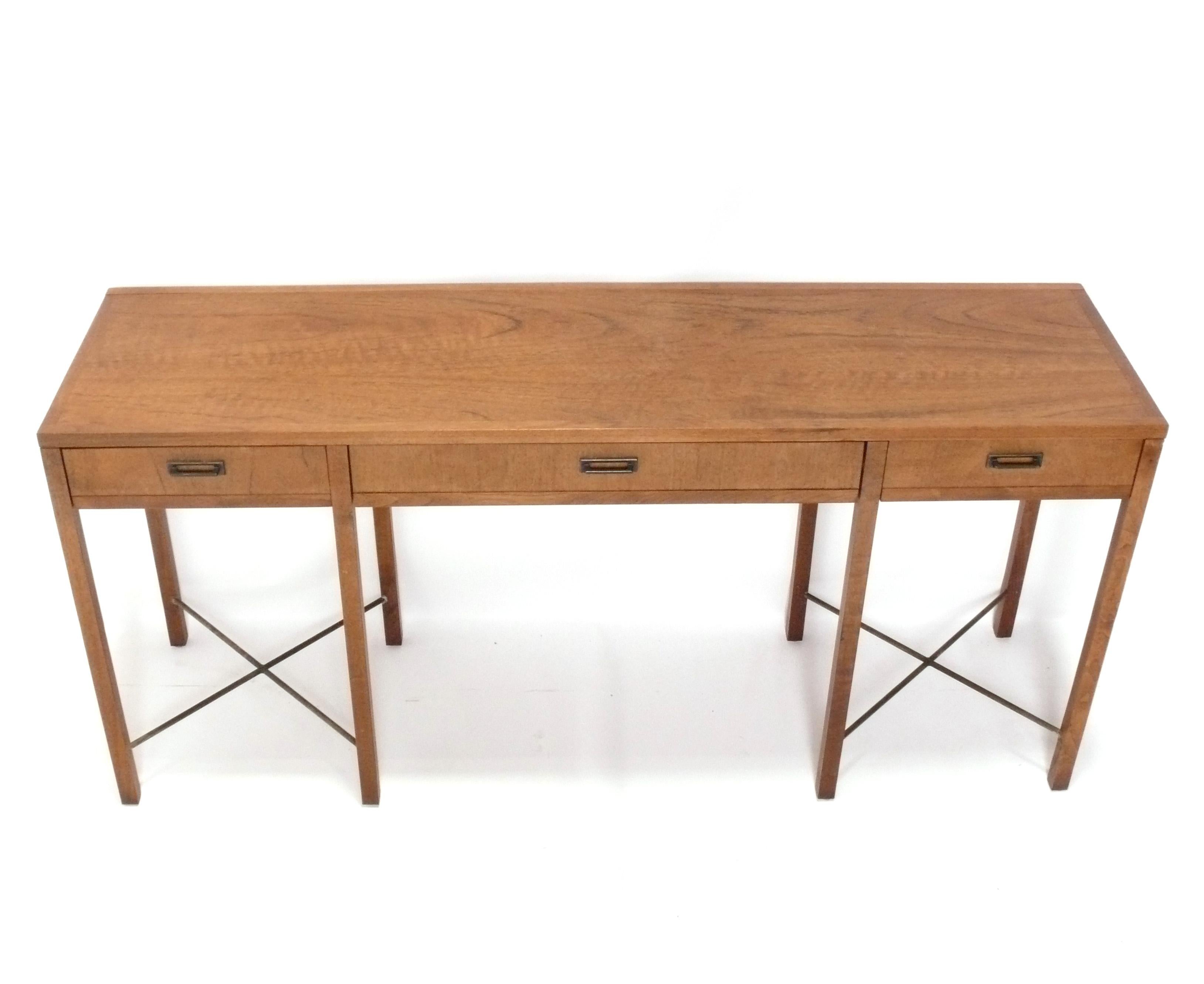 Élégante table console en noyer et base en X en laiton, conçue par Jack Cartwright pour Founders, américain, vers les années 1970. Cette table est actuellement en cours de finition et peut être complétée dans la couleur de votre choix sans frais