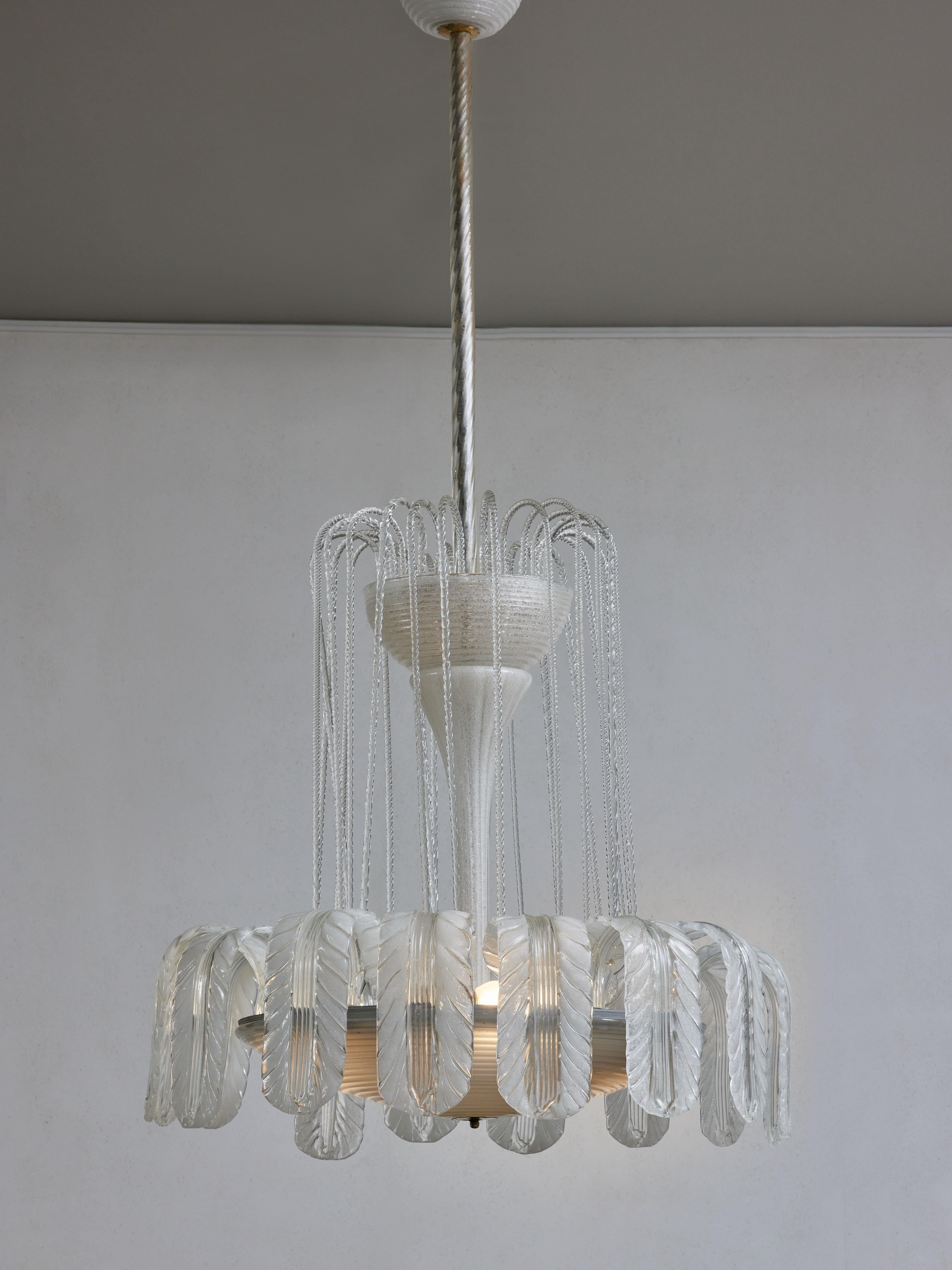 Stunning vintage chandelier from the 1930s in Murano glass and brass settings, by Barovier.
Several handmade delicate parts compose this amazing piece, ribbed hand opened clear etched glass canopy and bowls, fluted vertical tube to decorate the