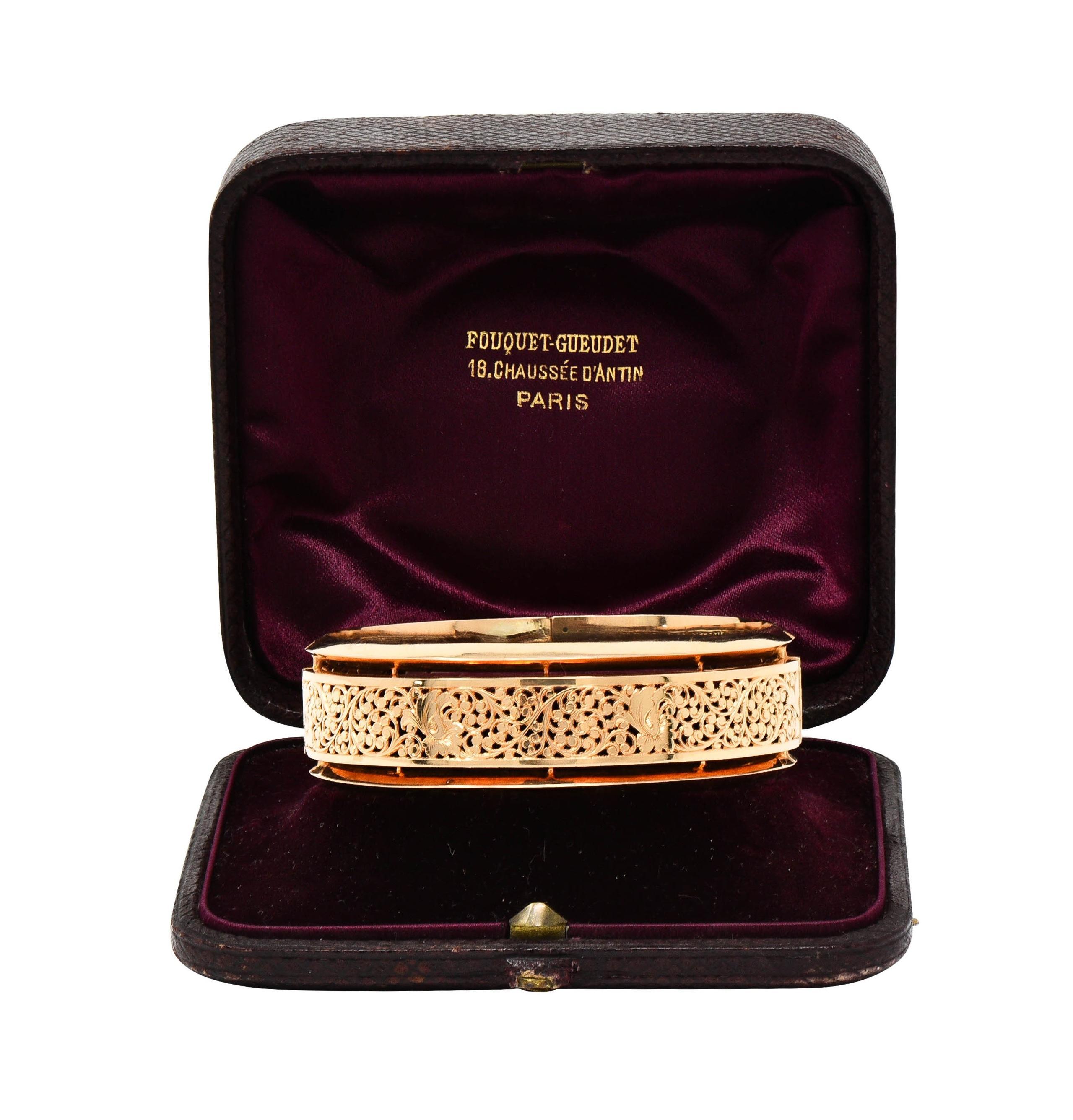 Featuring a pierced central panel displaying a fanning floral motif with scrolling vines
With a faceted knife edge frame surround - high polished
Panel is segmented with a hinged opening 
Completed by press release closure
With attached safety chain