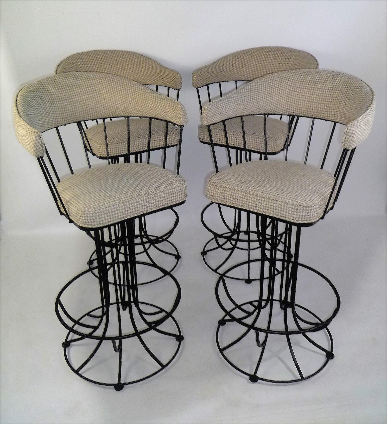 Wonderful 1960s swiveling barstools reminiscent of the shape and style created by Anton Lorenz. In shaped blackened iron, they have a circular design from the spindle back down to the bases. Freshly upholstered curved back and arms and seat in a