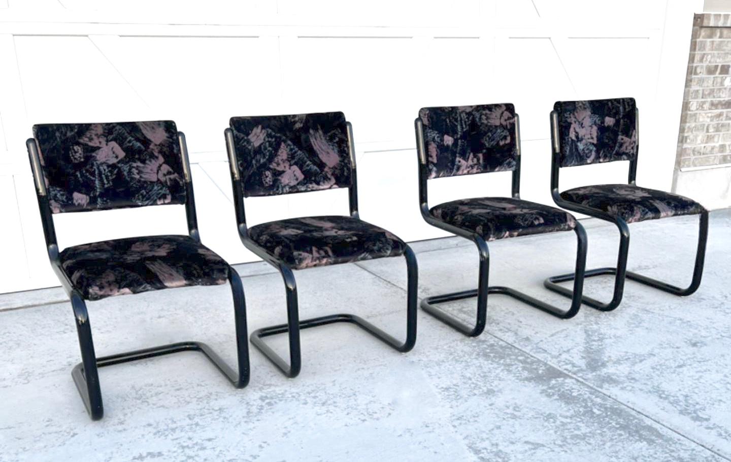 Four post-modern tubular cantilever chairs manufactured by Douglas Furniture. Features jet black enameled metal tube frames with soft iconic suede-like material featuring pastel brushstrokes of light blue and pink. The chairs and fabric are in