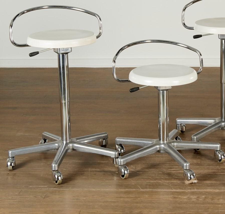 20th c., four mid-century modern adjustable height chrome drafting stools on casters, with white lacquered oak seats. In the style of Marcel Breuer. The stools can be adjusted from counter to bar height. These are very versatile stools that can be